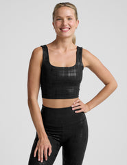 model wearing a black plaid foil printed square neck cropped tank top and matching leggings against a plain background.