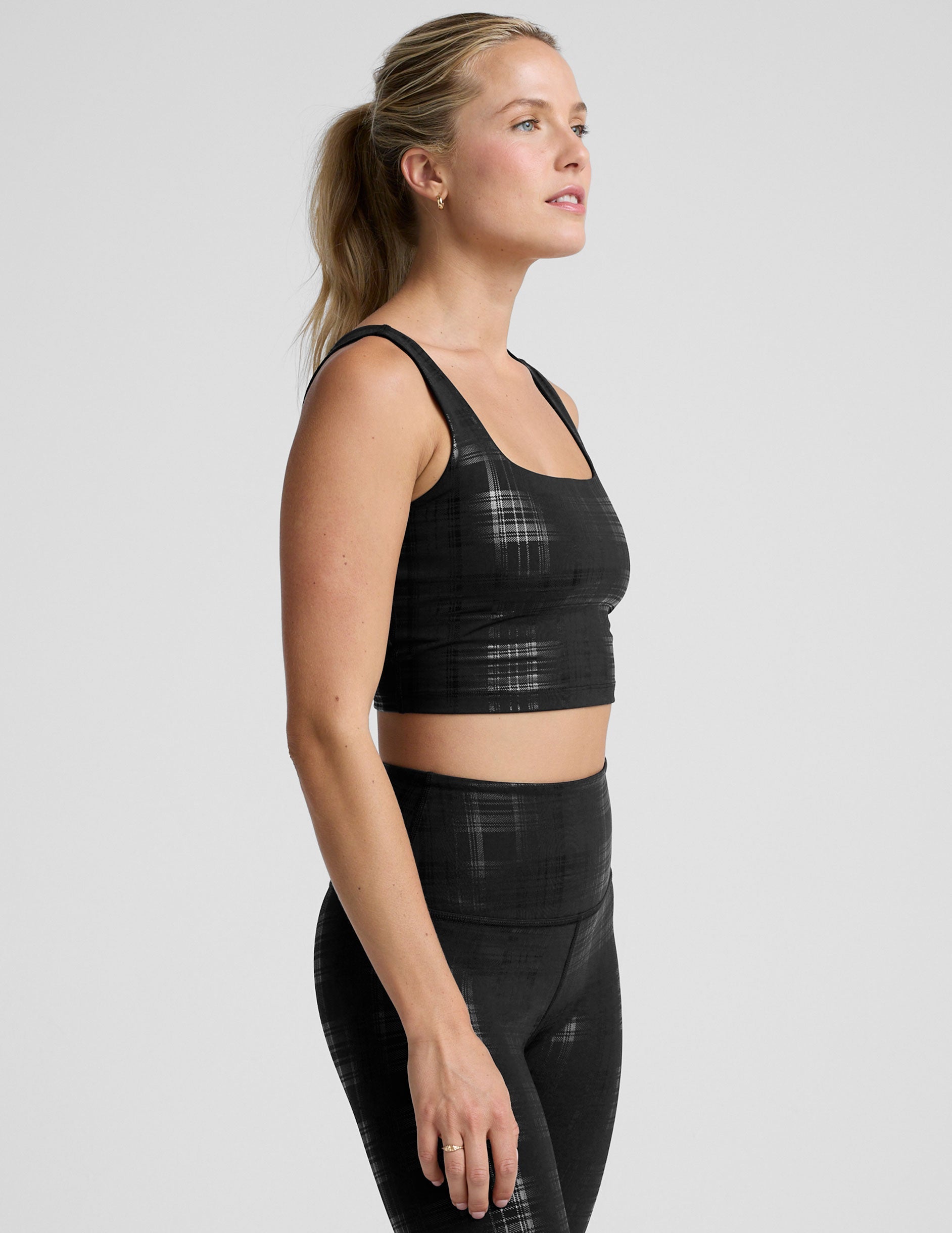 model wearing a black plaid foil printed square neck cropped tank top and matching leggings against a plain background.