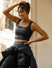 model wearing a black plaid foil printed square neck cropped tank top and matching leggings against a plain background.