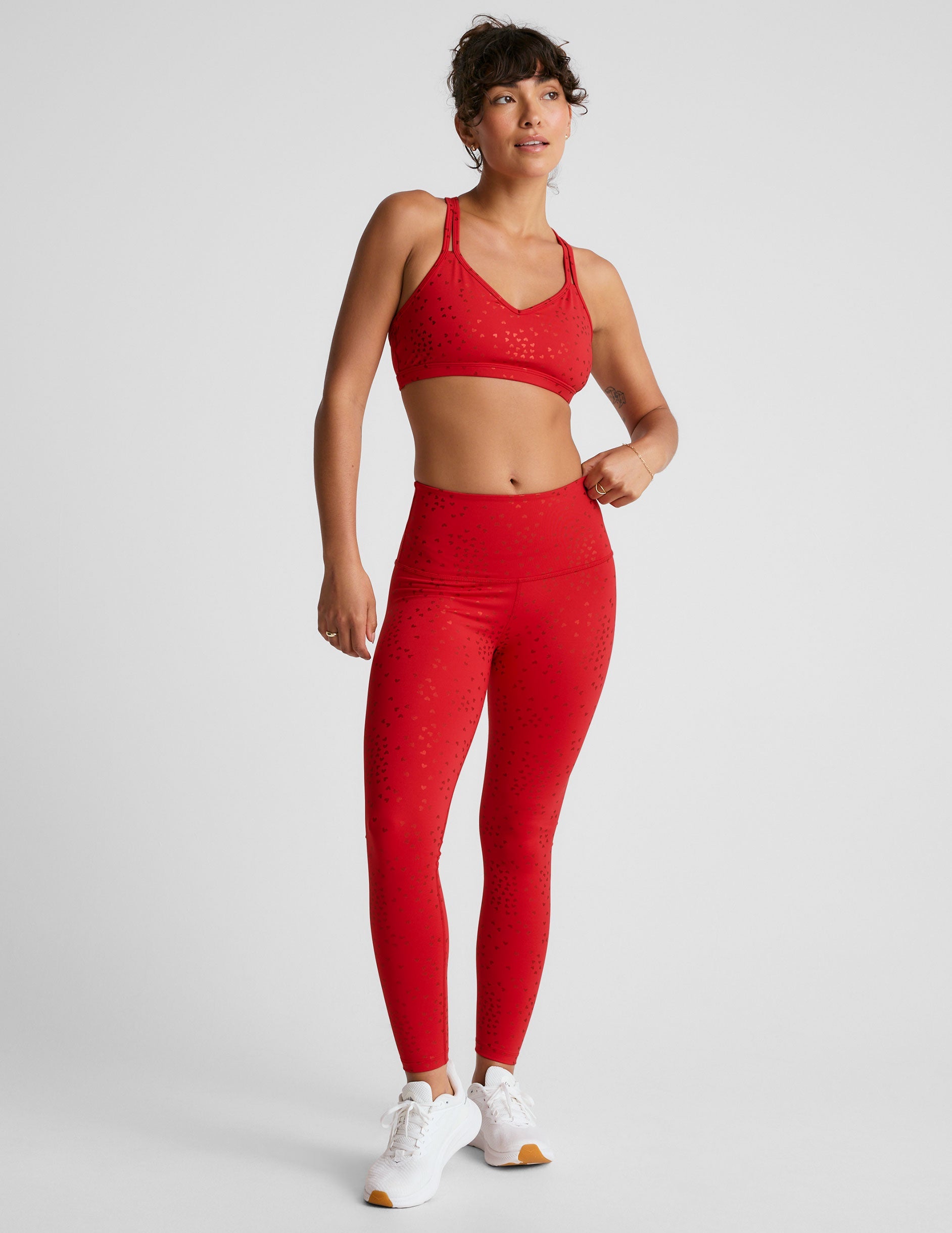 red high-waisted midi length leggings with a shimmering heart pattern.