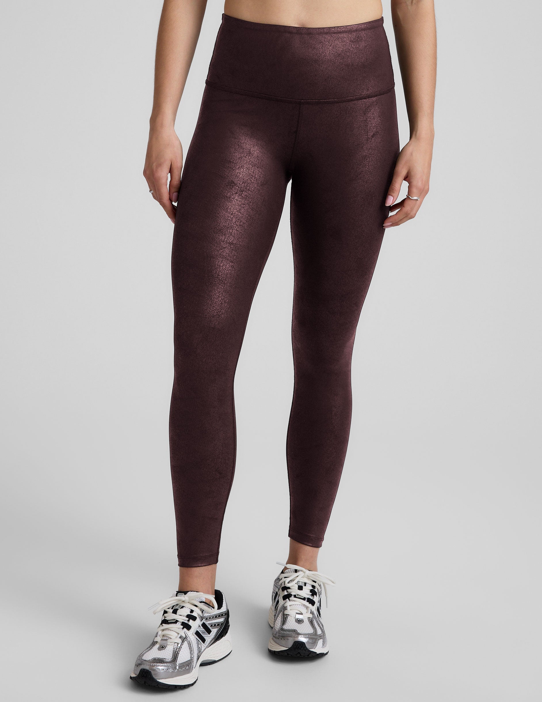 model wearing faux leather maroon leggings on a light gray background.