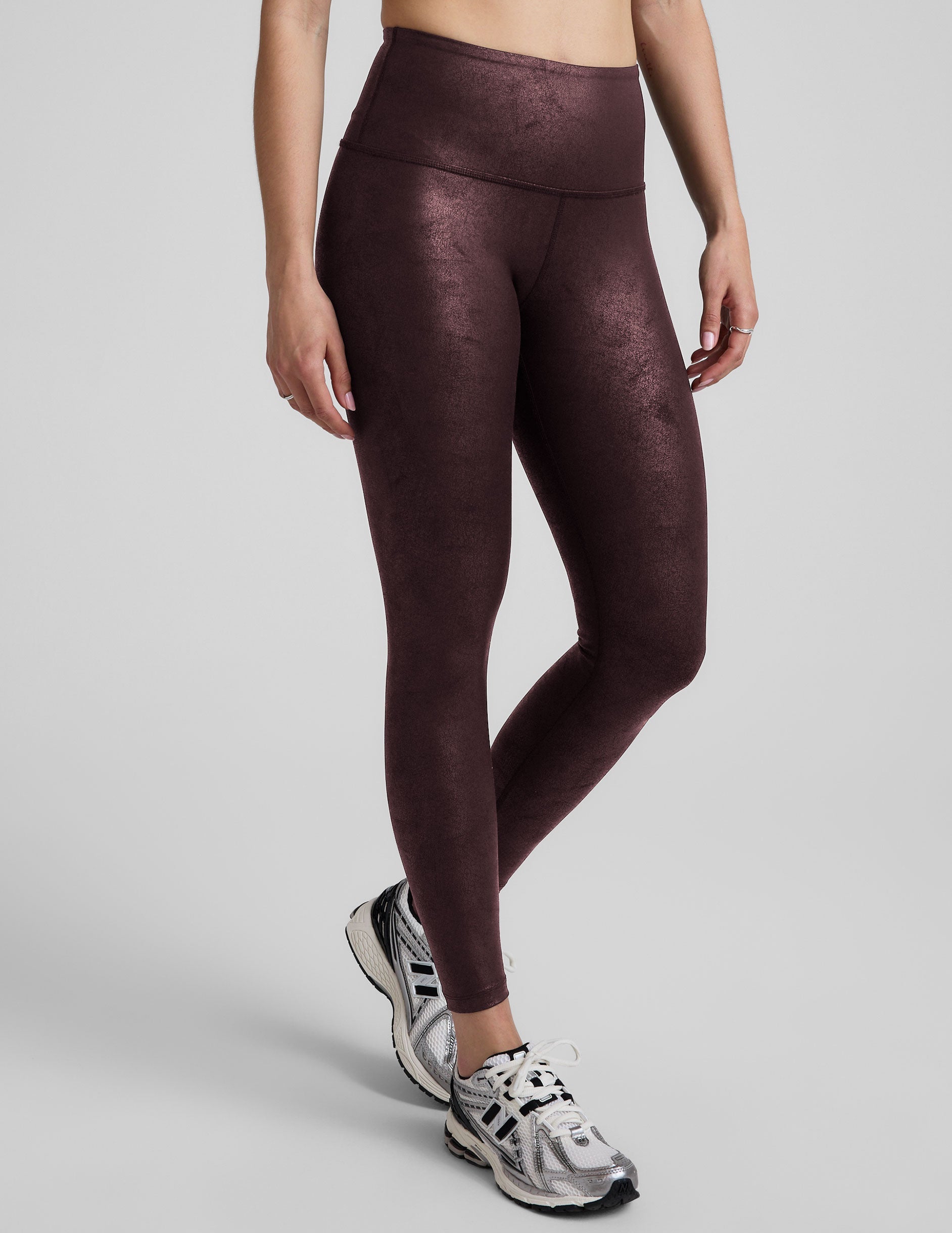 model wearing faux leather maroon leggings on a light gray background.