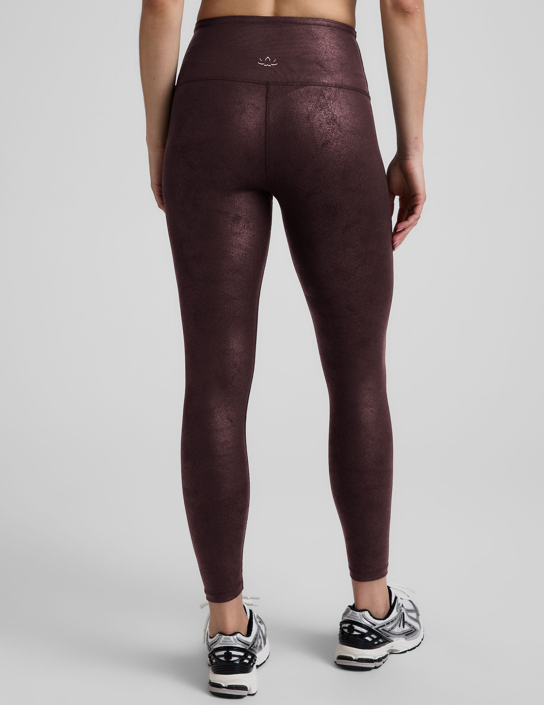 model wearing faux leather maroon leggings on a light gray background.