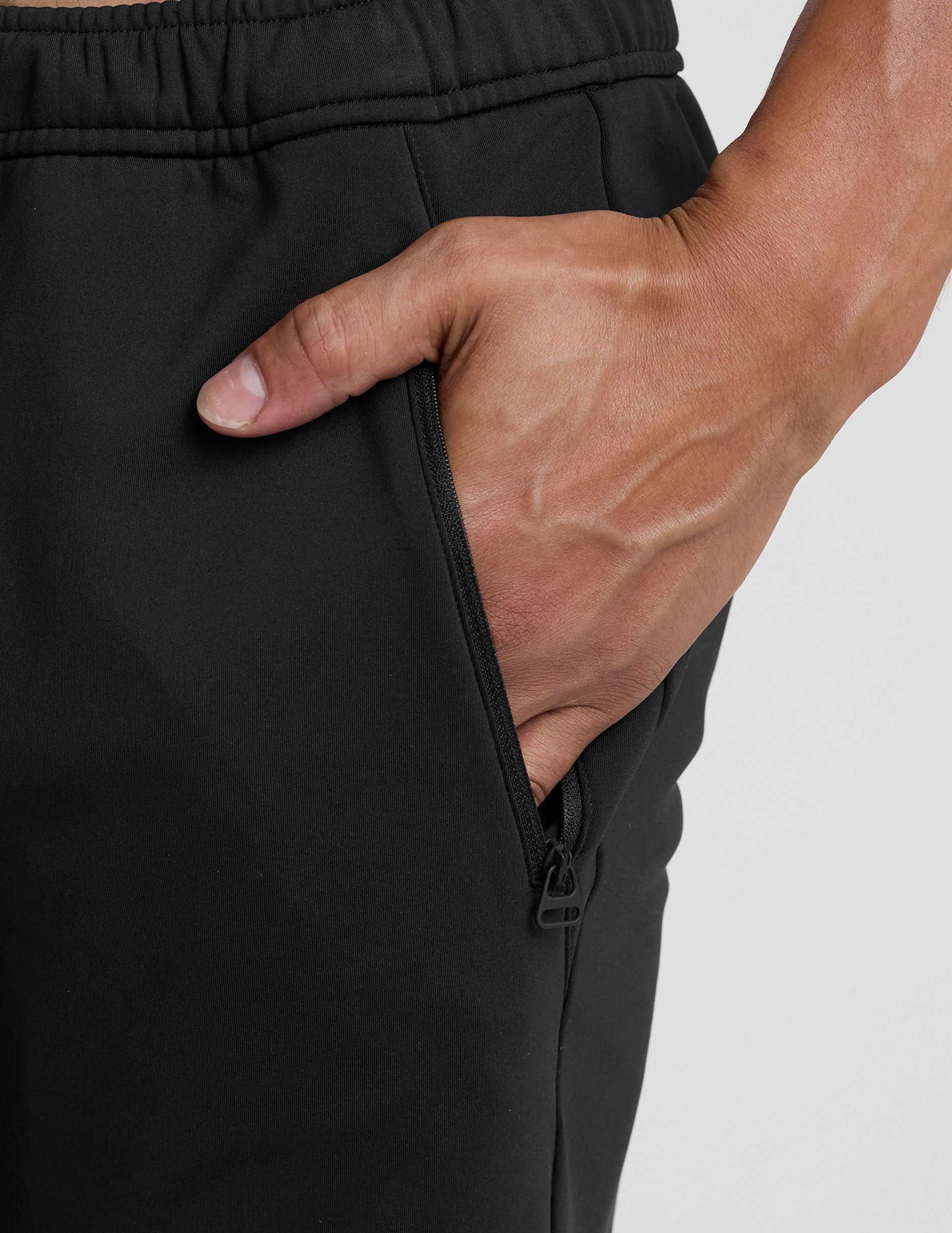 person wearing black pants and white sneakers on a light gray background