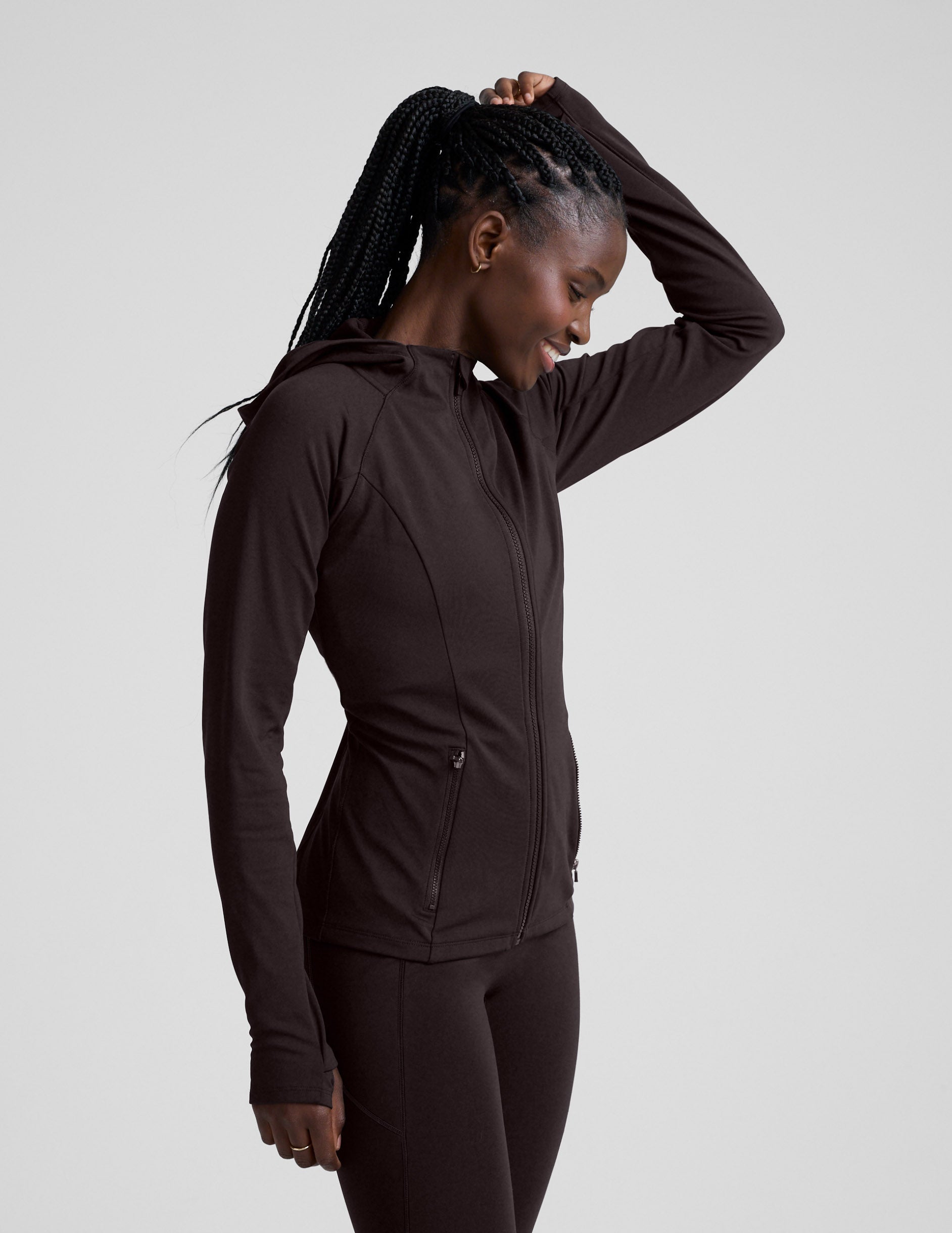 Woman wearing a brown full zip fleece lined jacket and leggings against a light gray background.