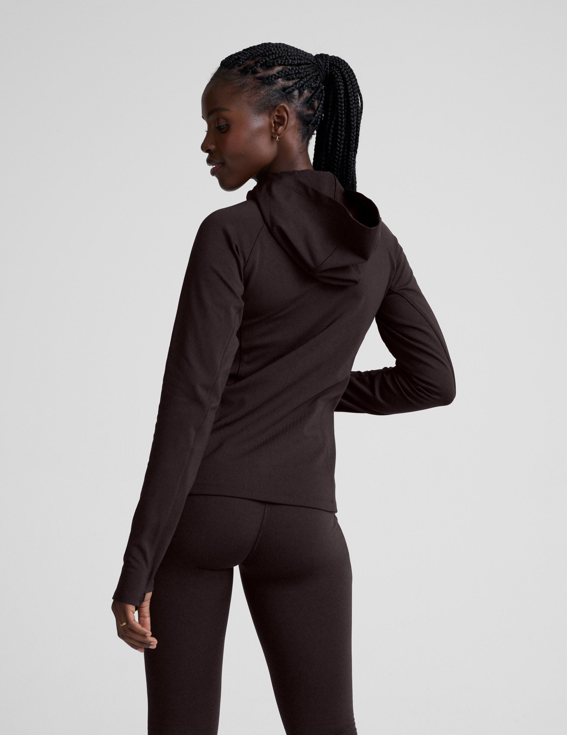 Woman wearing a brown full zip fleece lined jacket and leggings against a light gray background.