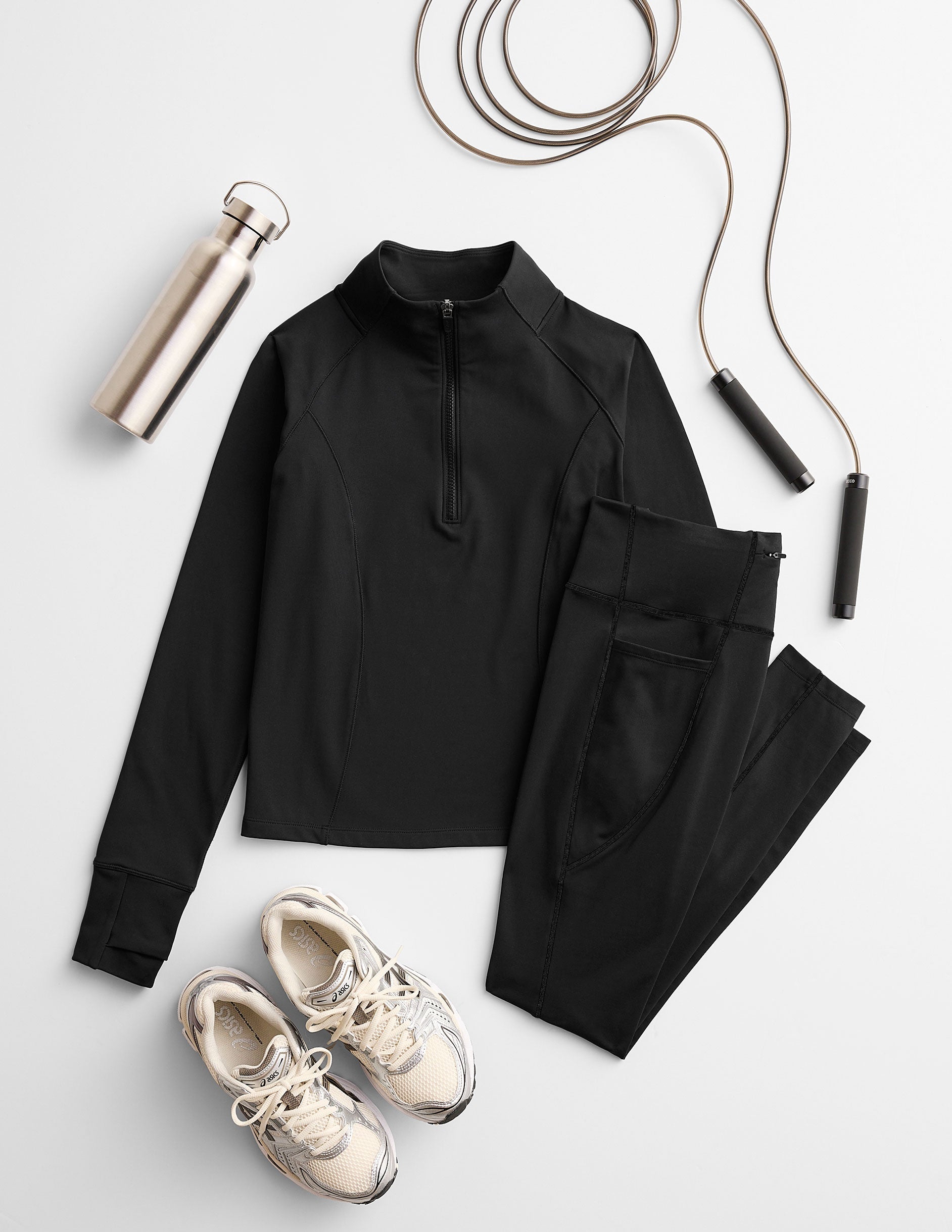 black athletic outfit with sneakers and jump rope on a light gray background.