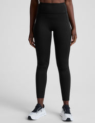 woman wearing a black high-waisted long length leggings with pockets athletic outfit on a plain background.