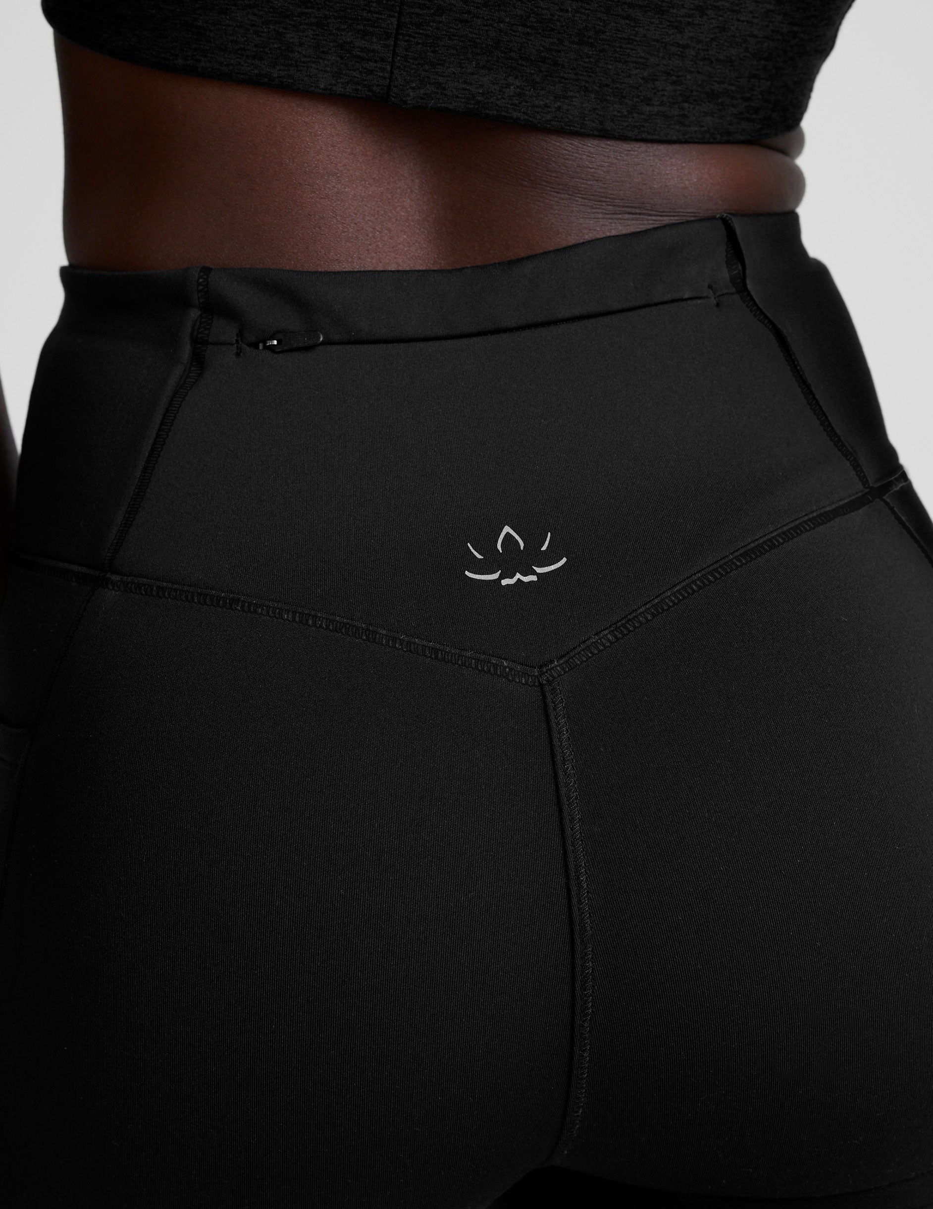 woman wearing a black high-waisted long length leggings with pockets athletic outfit on a plain background.