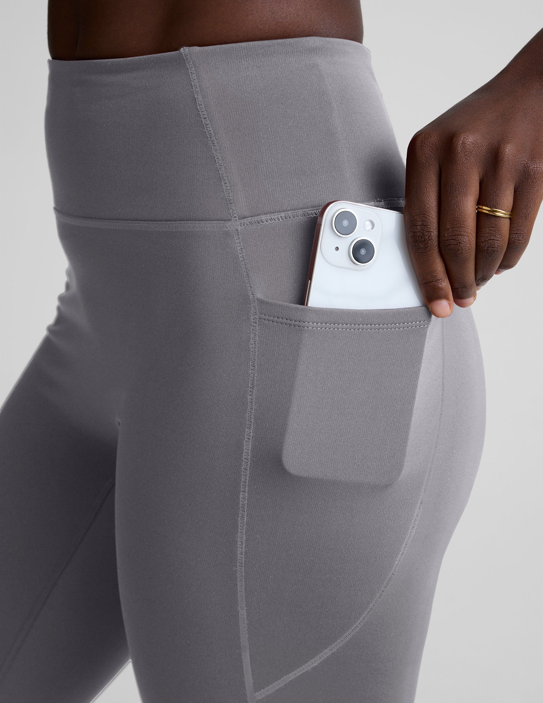 woman wearing gray high-waisted long length leggings on a plain background.