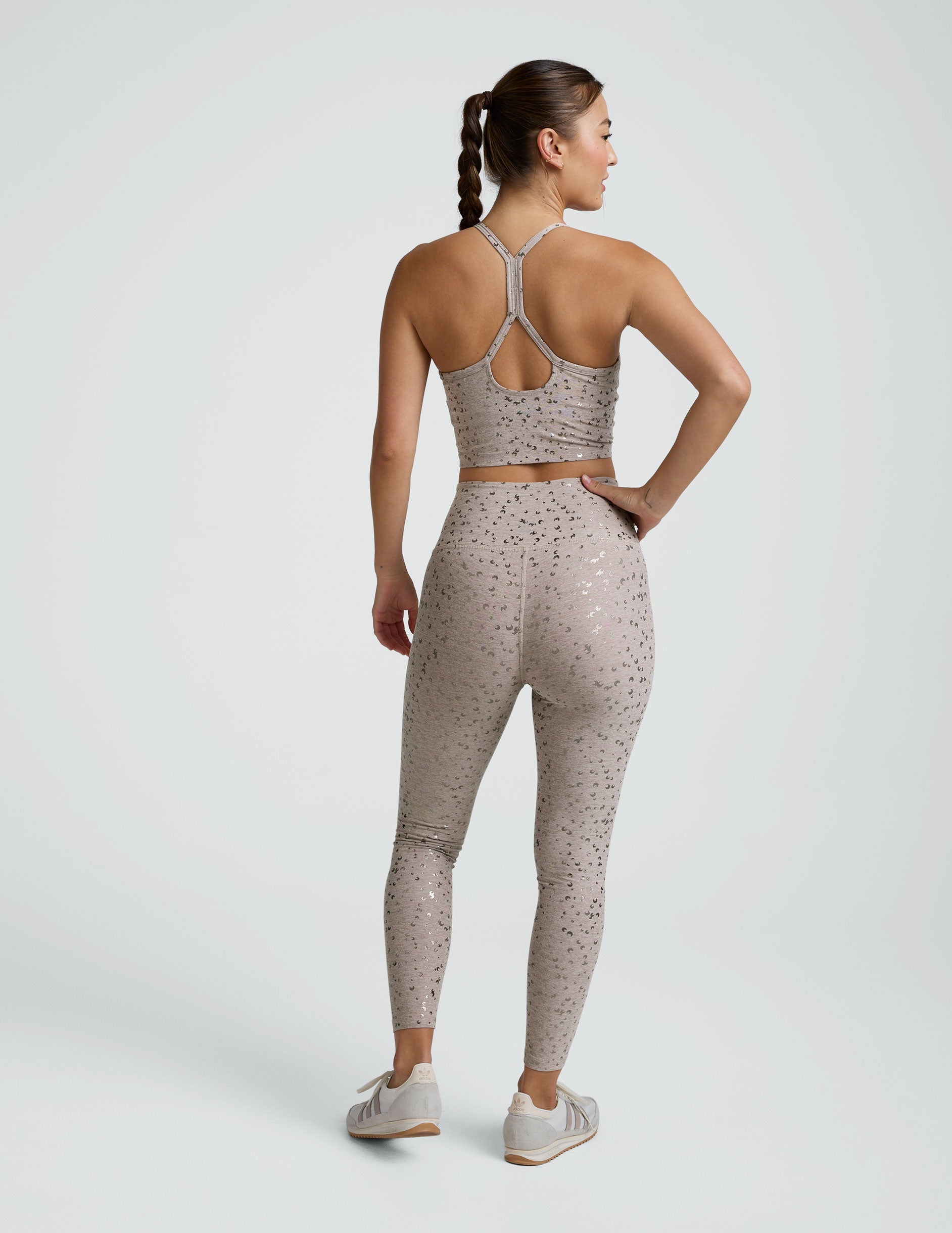 woman wearing high-waisted midi length beige leggings with a mini moon print against a plain background.
