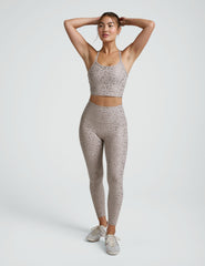 woman wearing high-waisted midi length beige leggings with a mini moon print against a plain background.