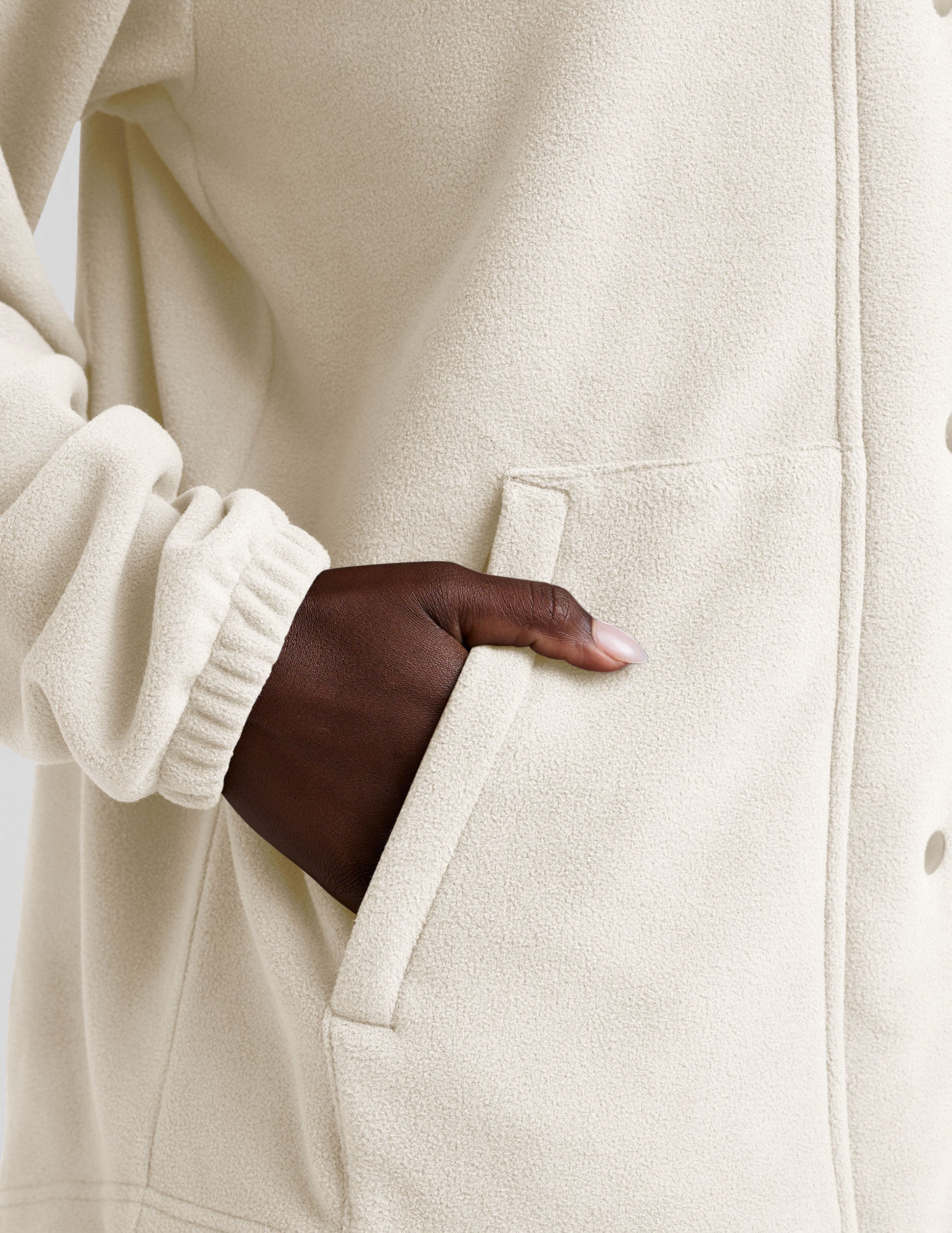 white fleece button up jacket with a full front zip and snap closures and pockets.