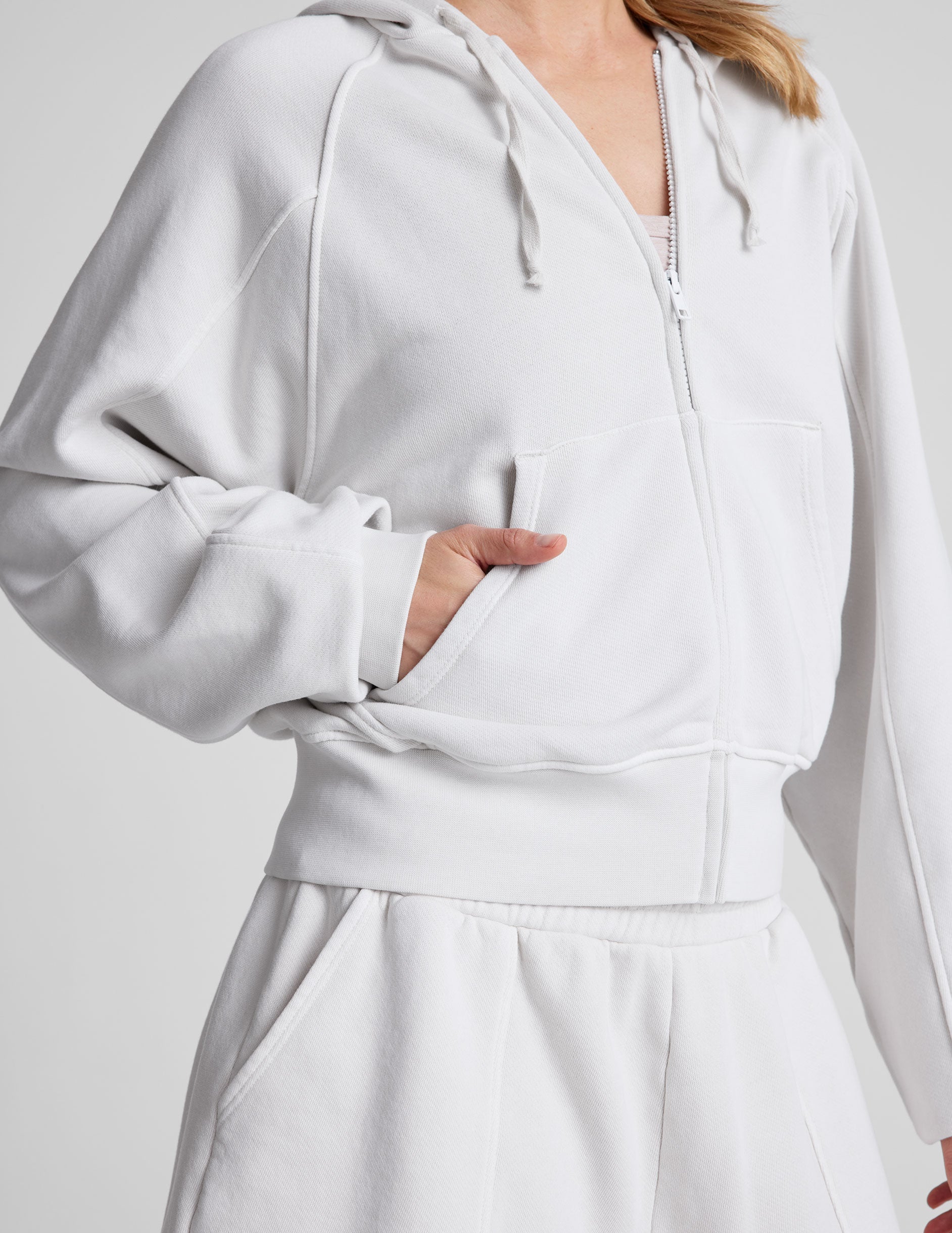 white zip-up jacket with hoodie and pockets.