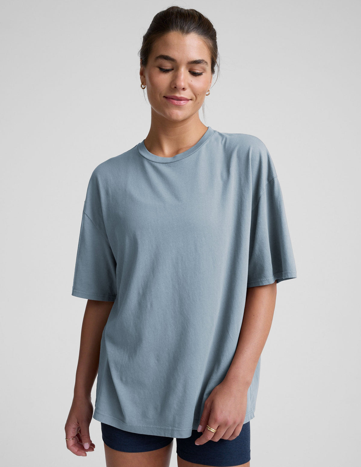 model wearing a light blue oversized cotton t-shirt and navy blue biker shorts against a plain background.