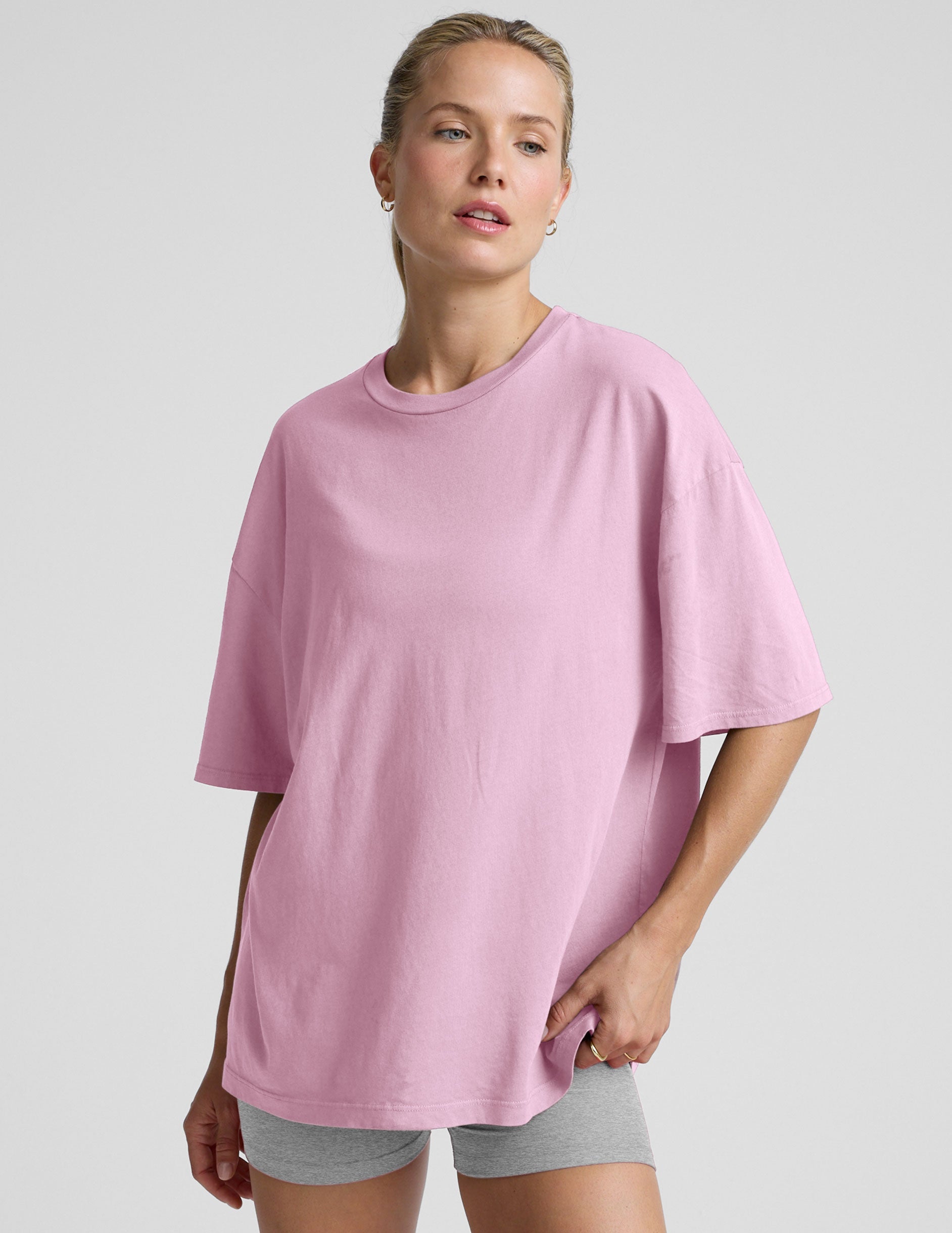 model wearing a pink oversized cotton t-shirt and grey biker shorts against a plain background.