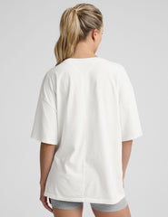 model wearing a white oversized cotton t-shirt and grey shorts against a plain background.