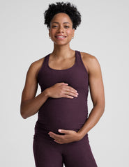 model wearing a purple maternity racerback tank top and leggings against a gray background.