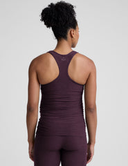 model wearing a purple maternity racerback tank top and leggings against a gray background.