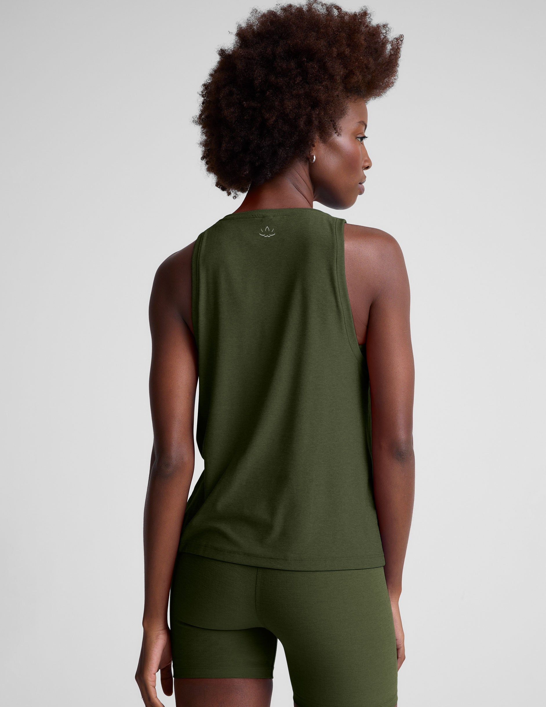 model wearing a green scoop neck tank top and leggings against a plain background.