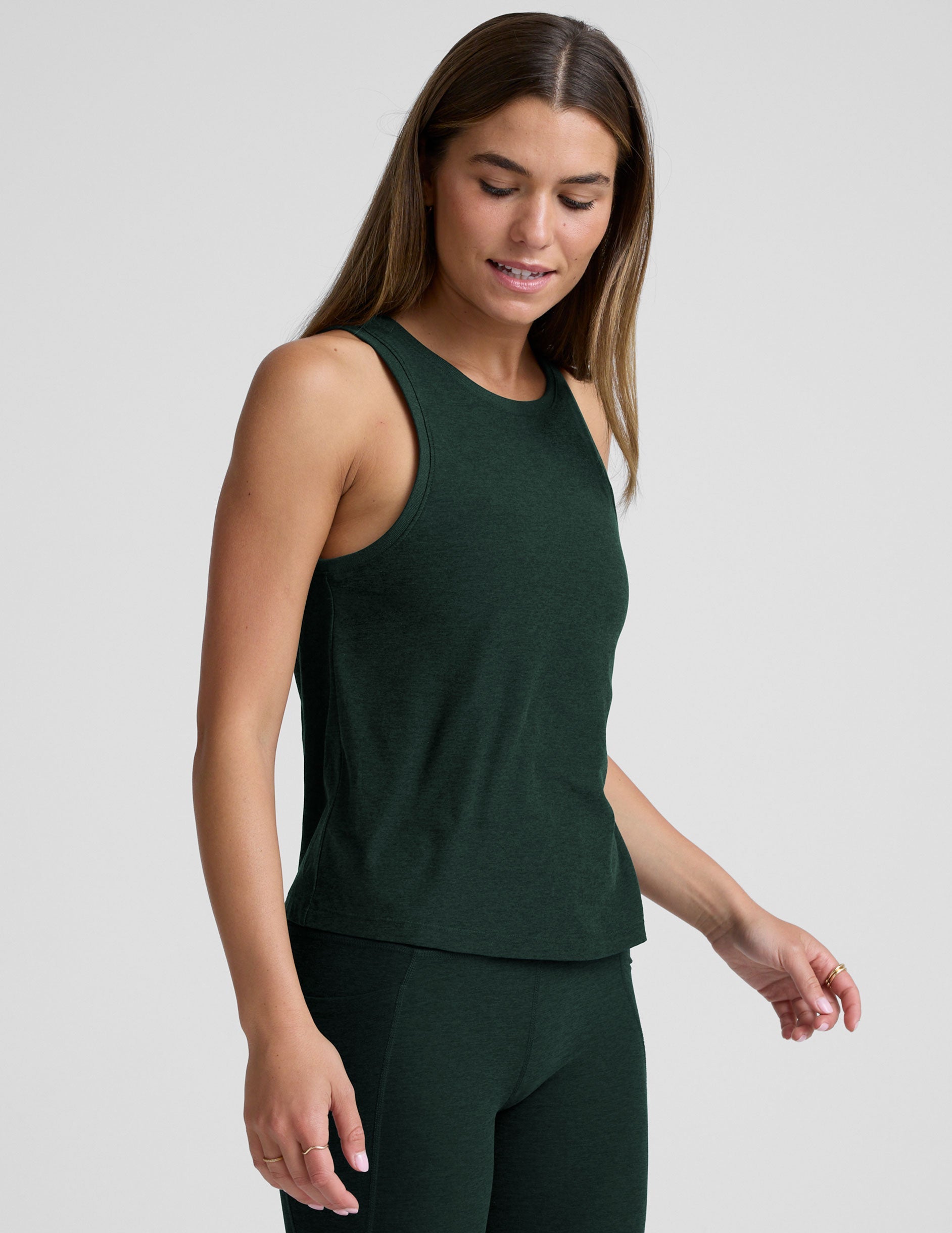 model wearing a green relaxed fit tank top and leggings against a plain background.