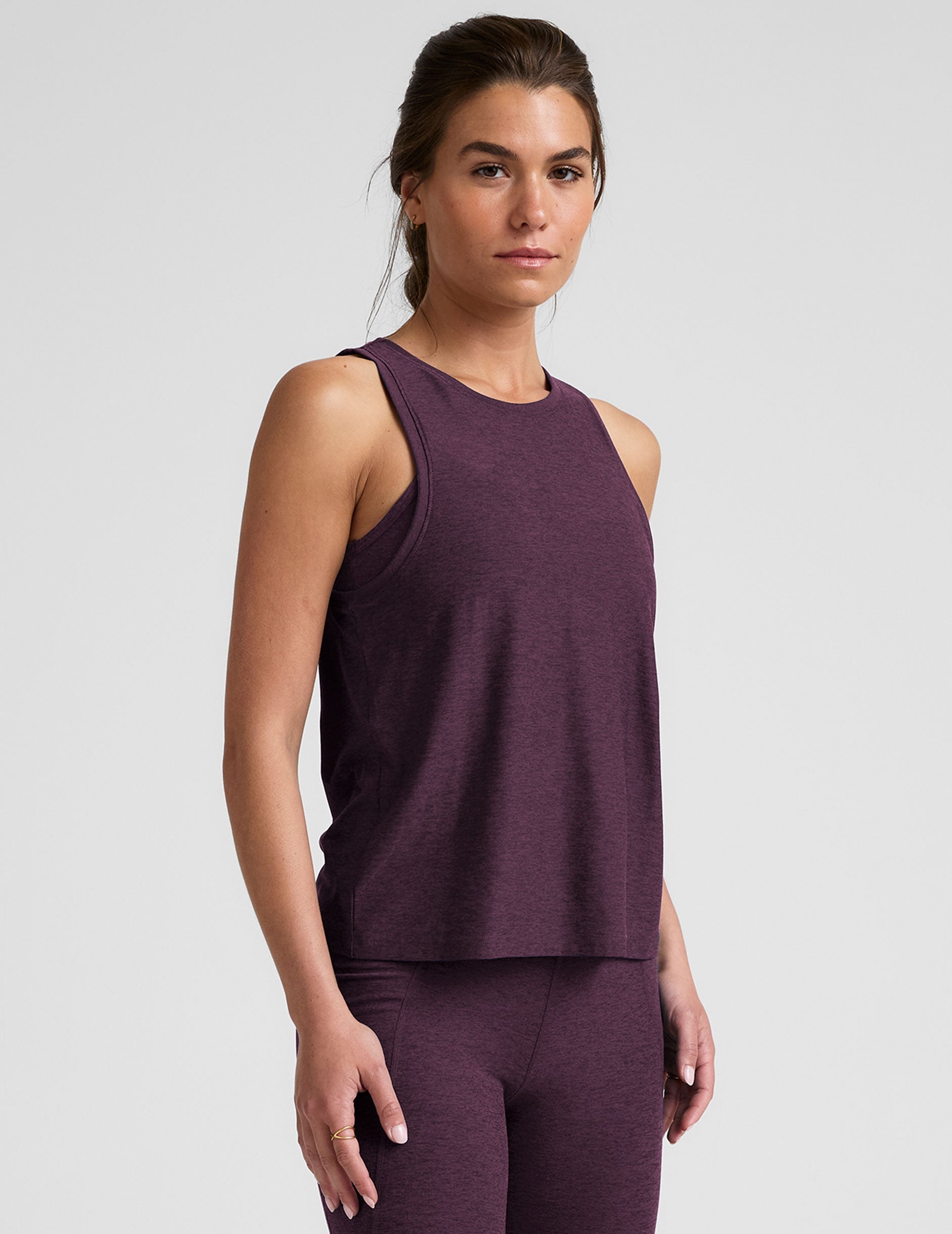 model wearing a purple relaxed fit tank top and leggings on a light gray background.
