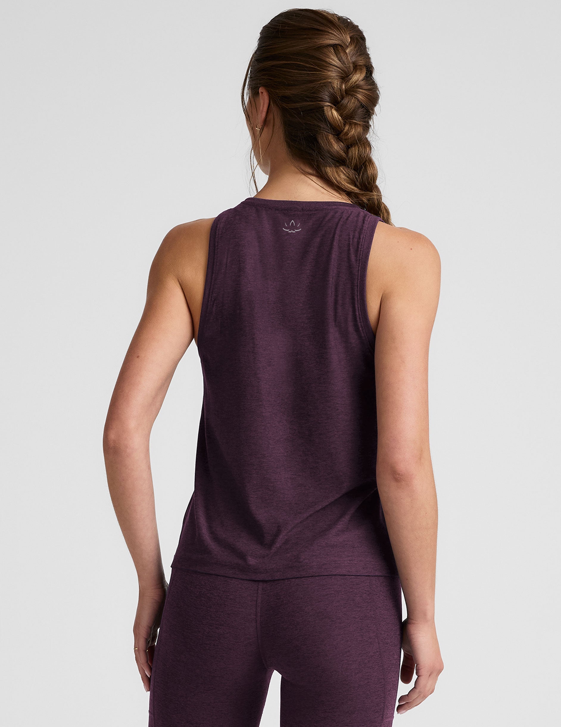 model wearing a purple relaxed fit tank top and leggings on a light gray background.