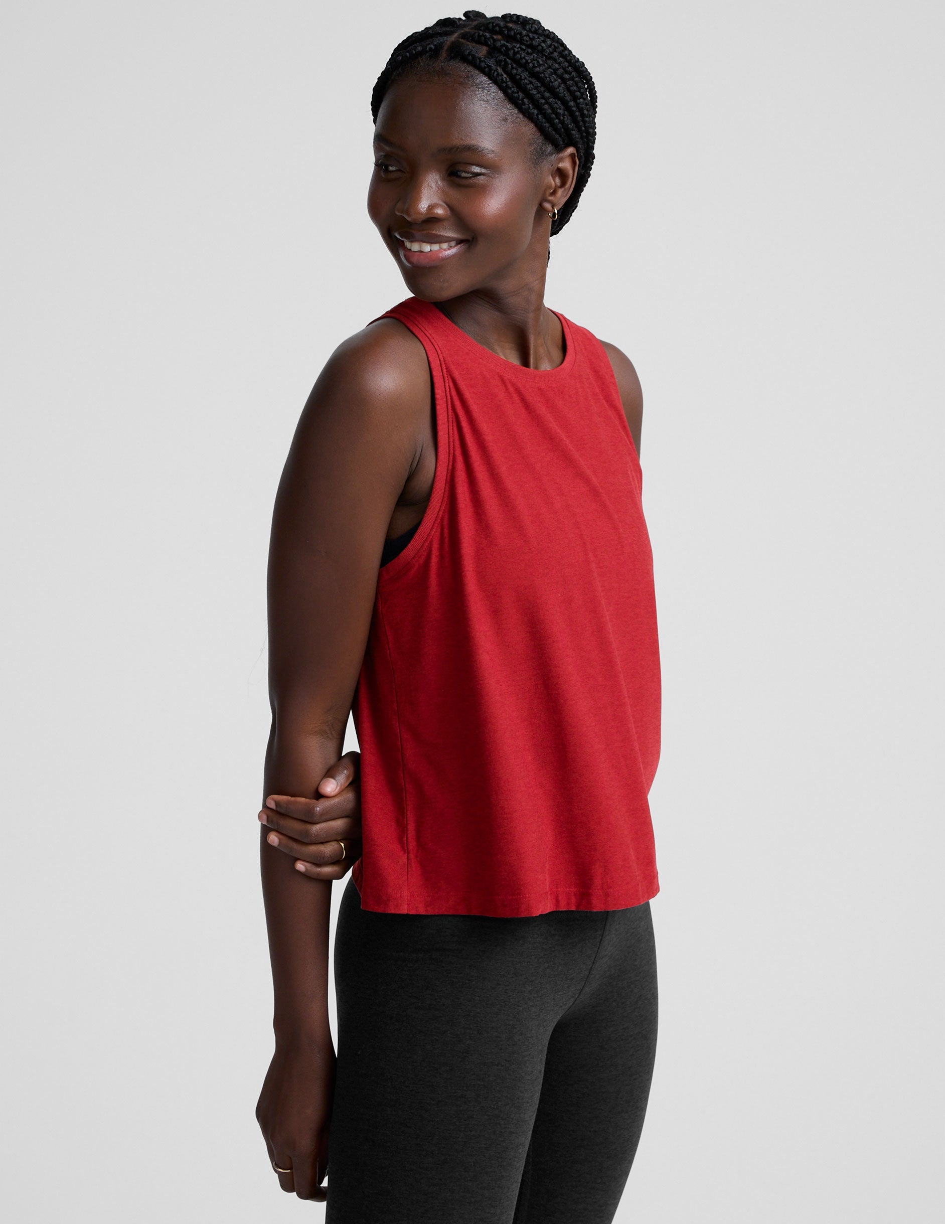 model wearing a red scoop neck sleeveless top and black leggings against a plain background.