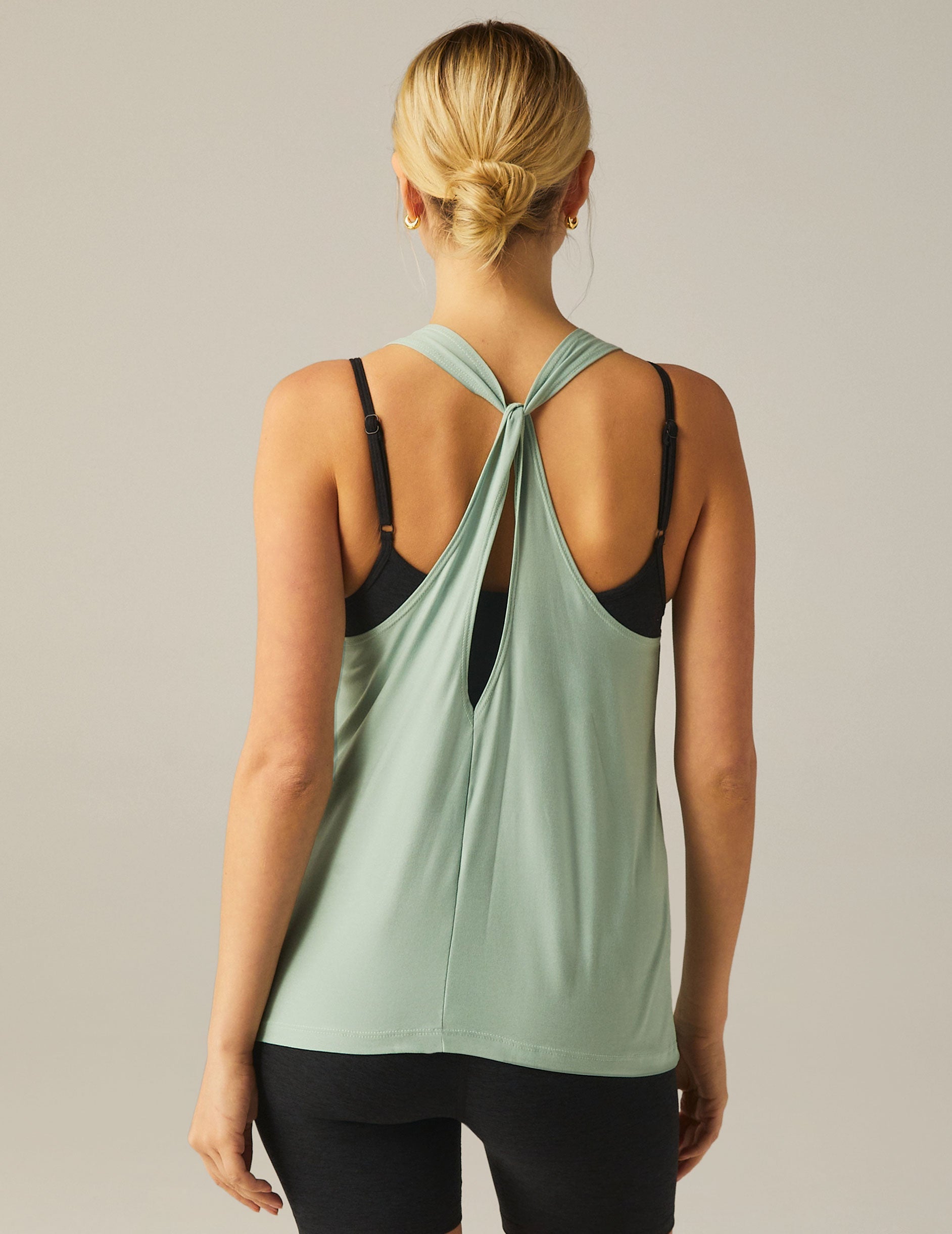 green high-neck tank top with a twist cutout detail on the back straps.