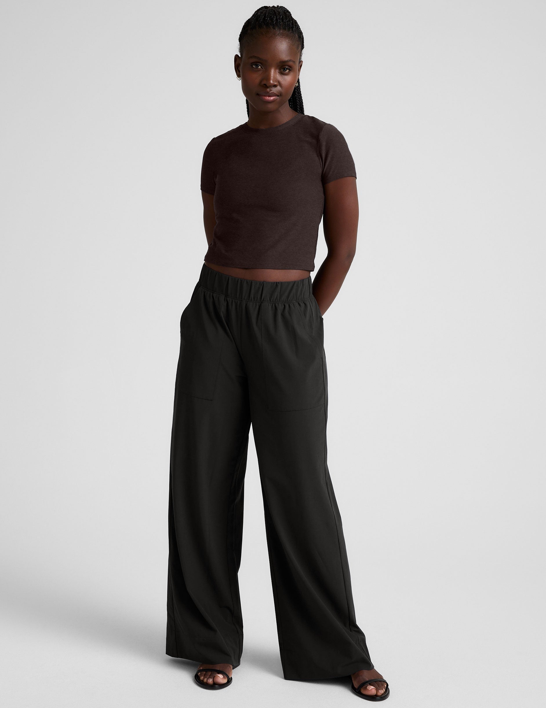 model wearing a brown crop top and black pants against a plain background.