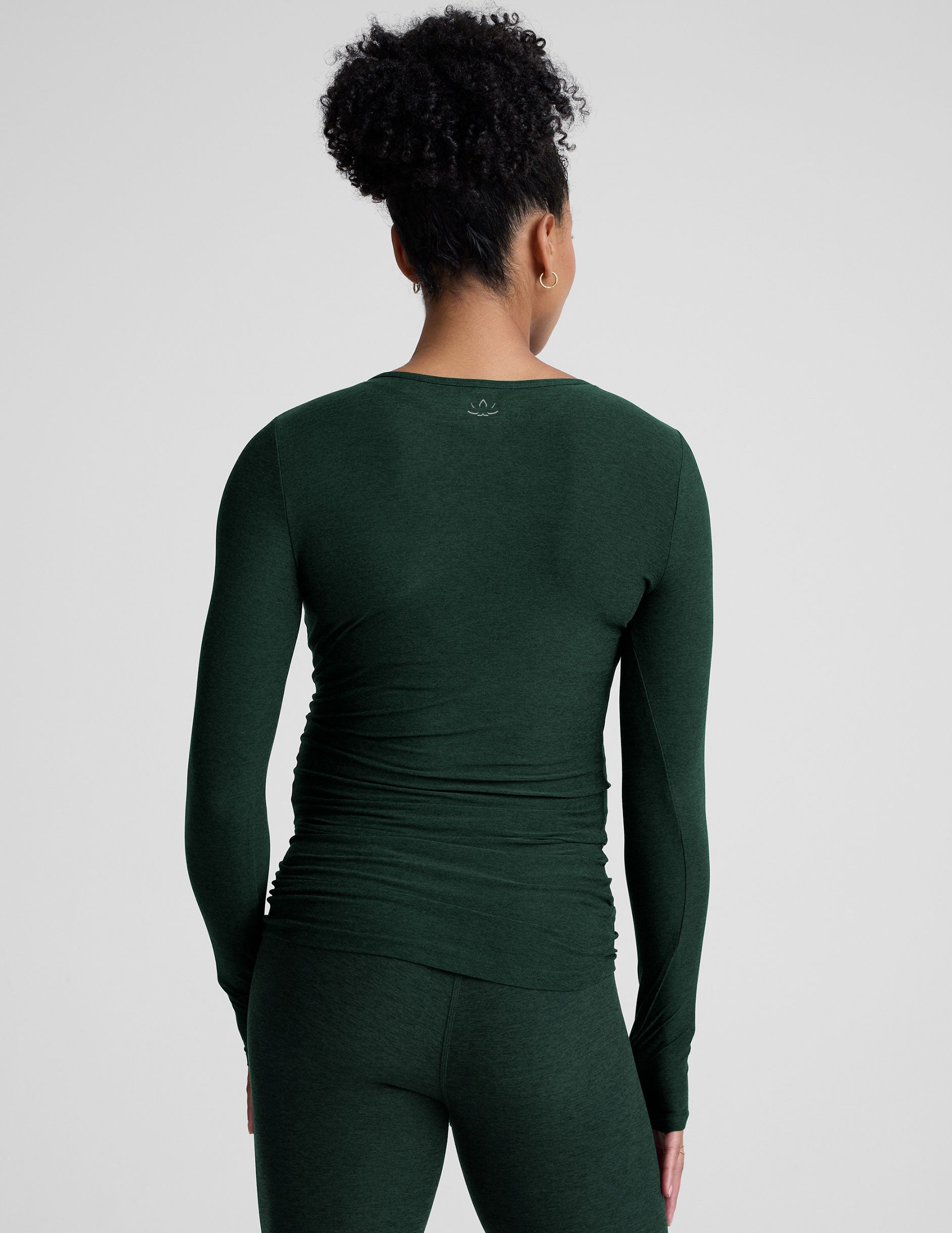 model wearing a green long-sleeve maternity top and leggings against a plain background.