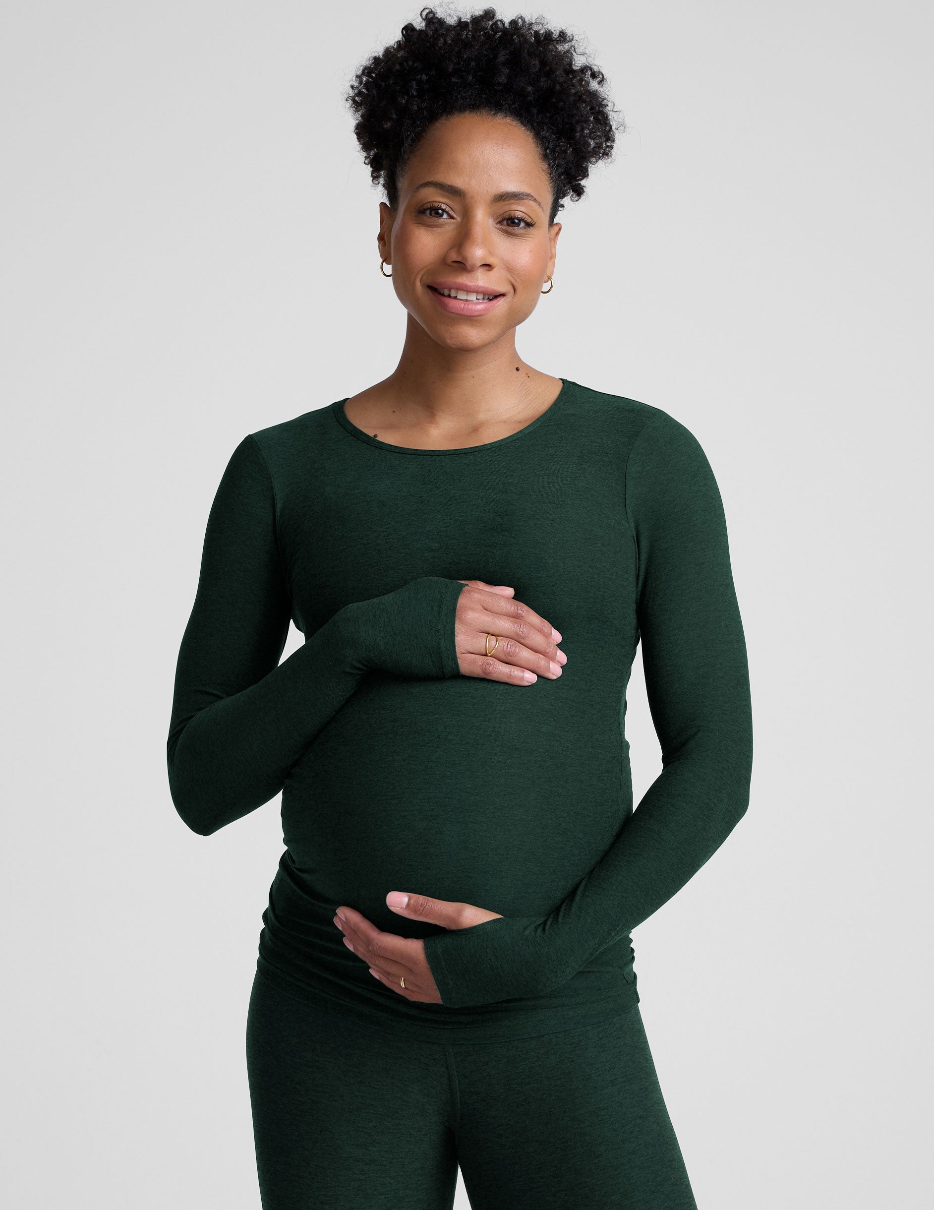model wearing a green long-sleeve maternity top and leggings against a plain background.