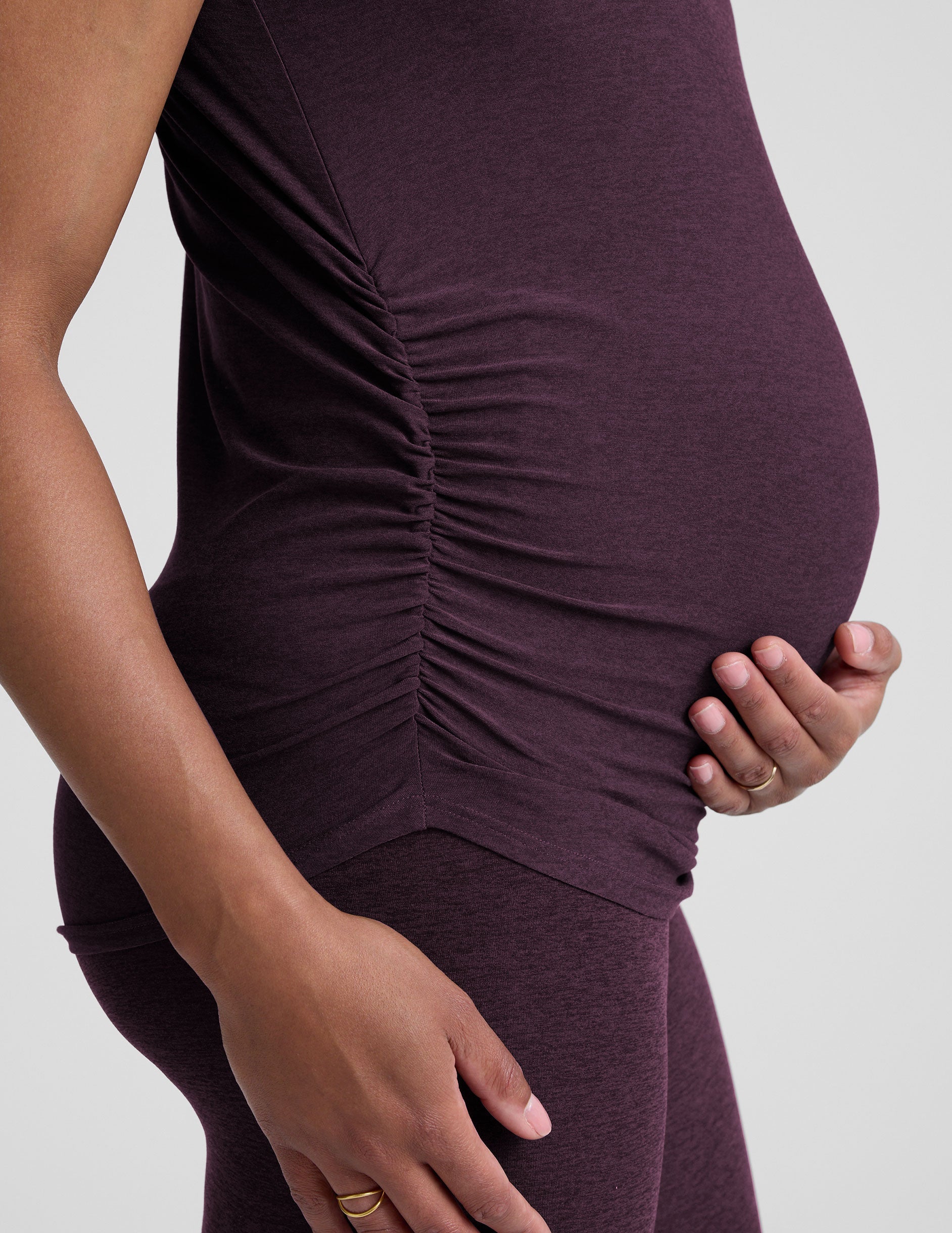 model wearing a purple maternity t-shirt and leggings against a light gray background.