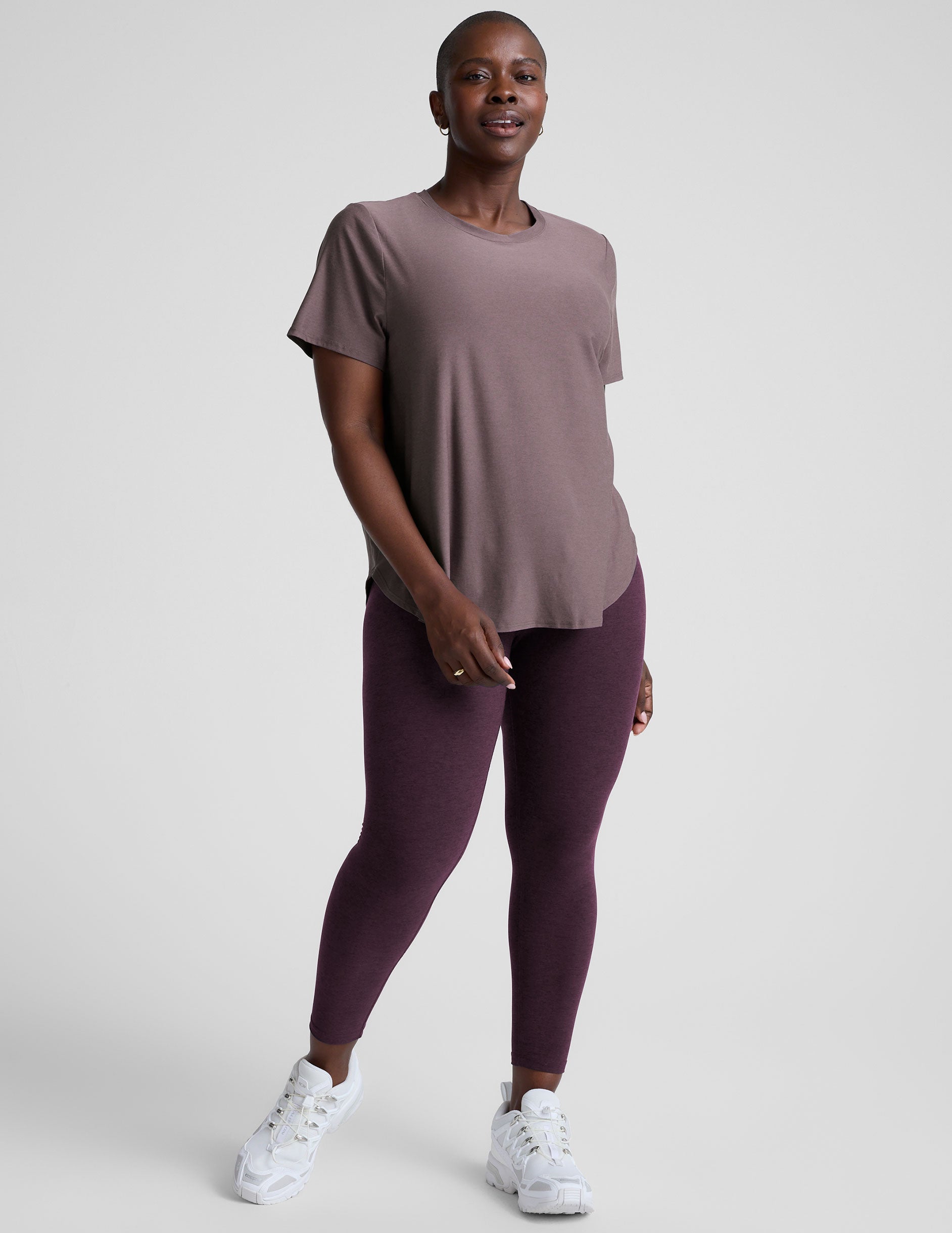model wearing a mauve t-shirt and leggings on a plain background.