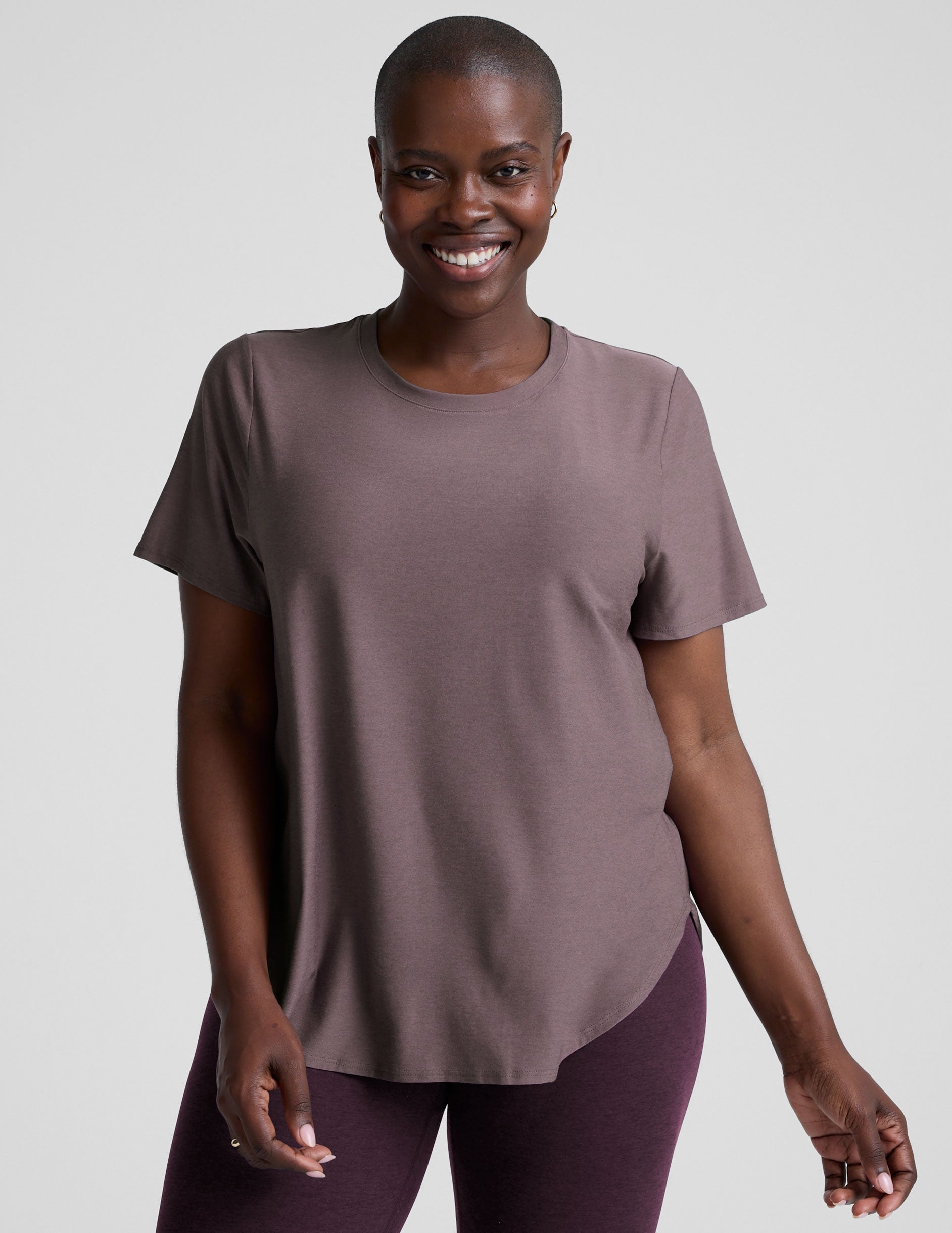 model wearing a mauve t-shirt and leggings on a plain background.