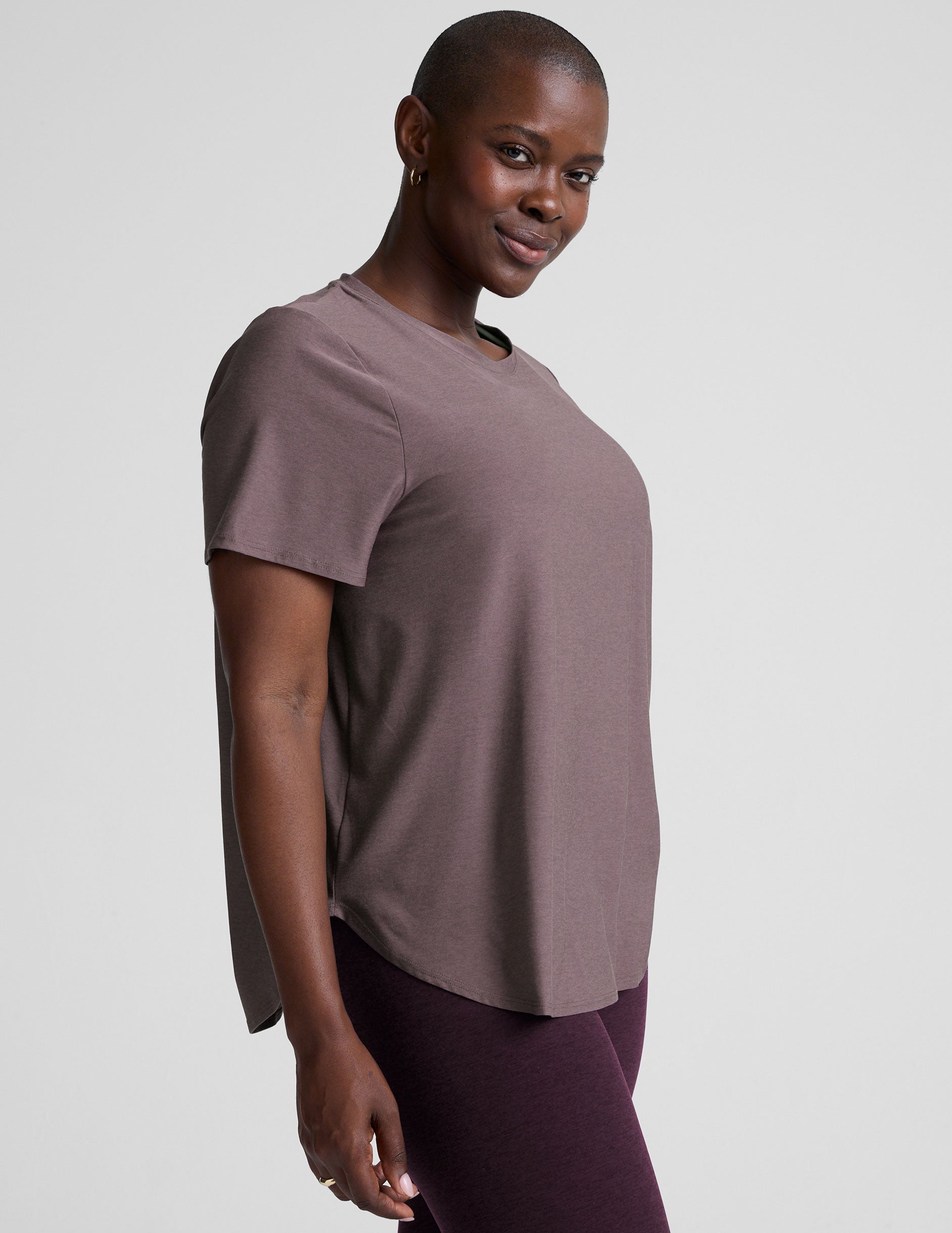 model wearing a mauve t-shirt and leggings on a plain background.