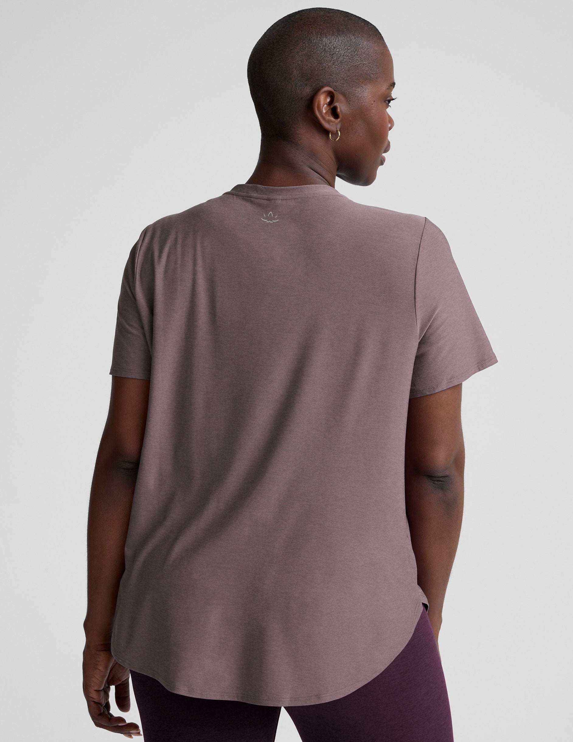 model wearing a mauve t-shirt and leggings on a plain background.