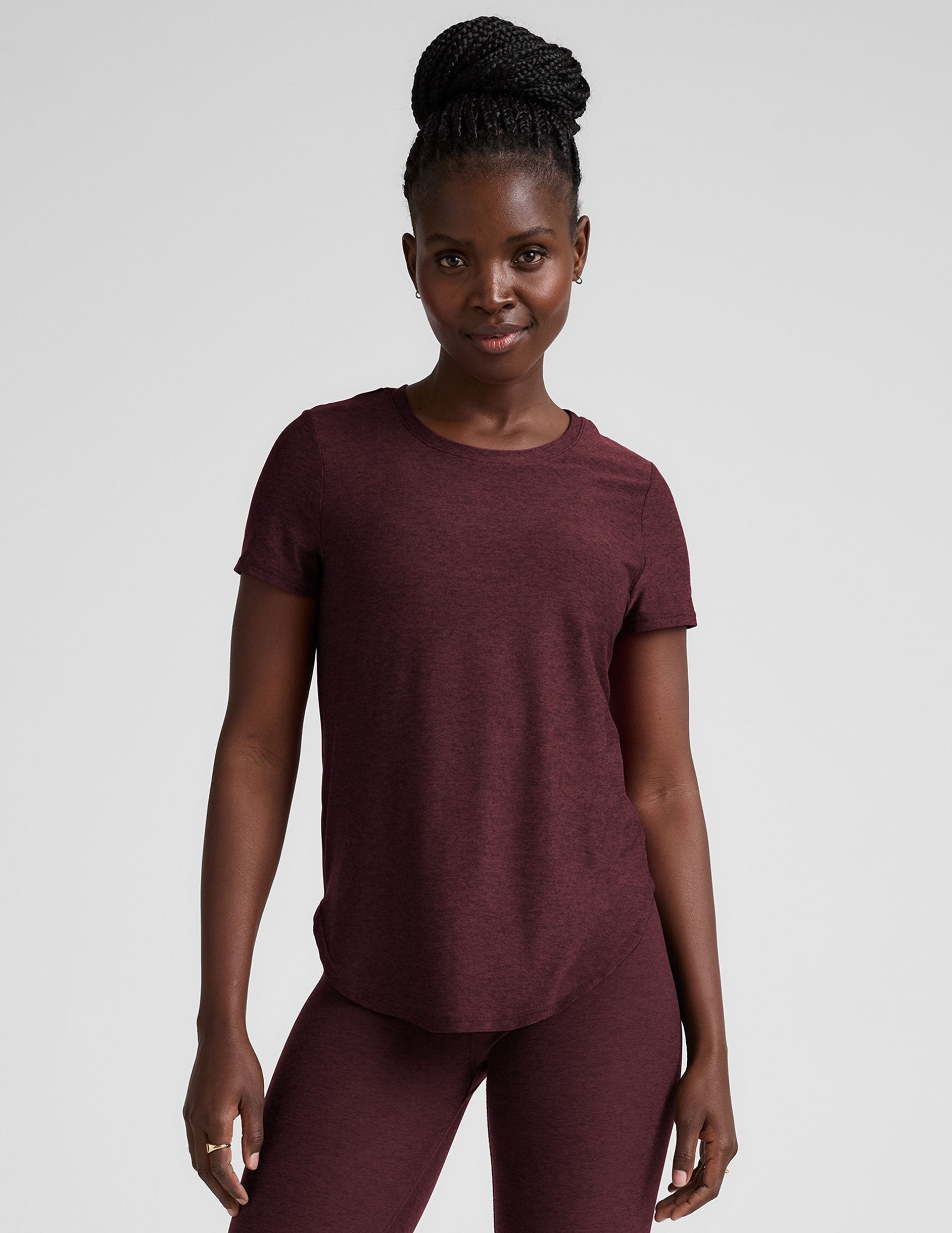 model is wearing a maroon t-shirt and leggings against a plain background.