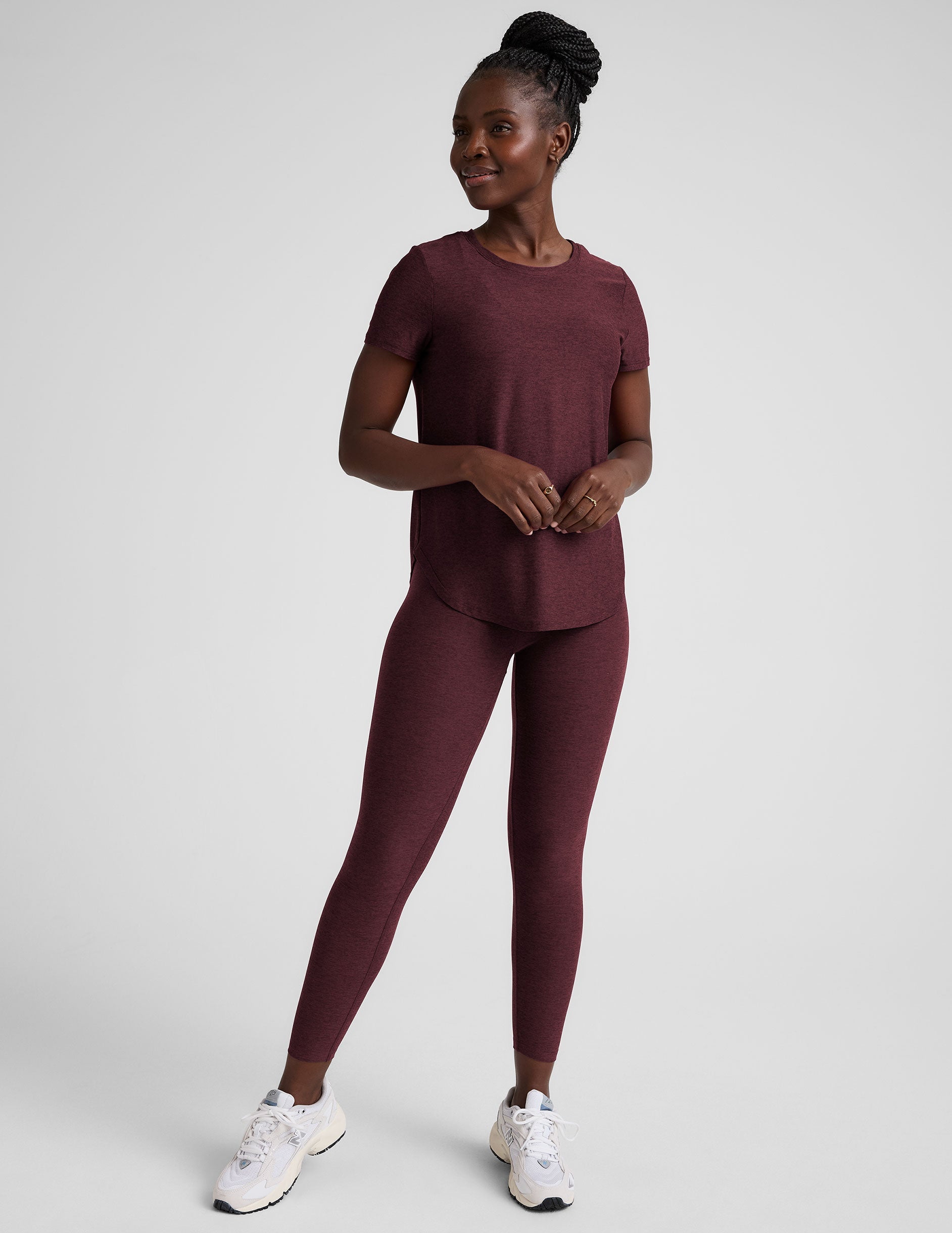 model is wearing a maroon t-shirt and leggings against a plain background.