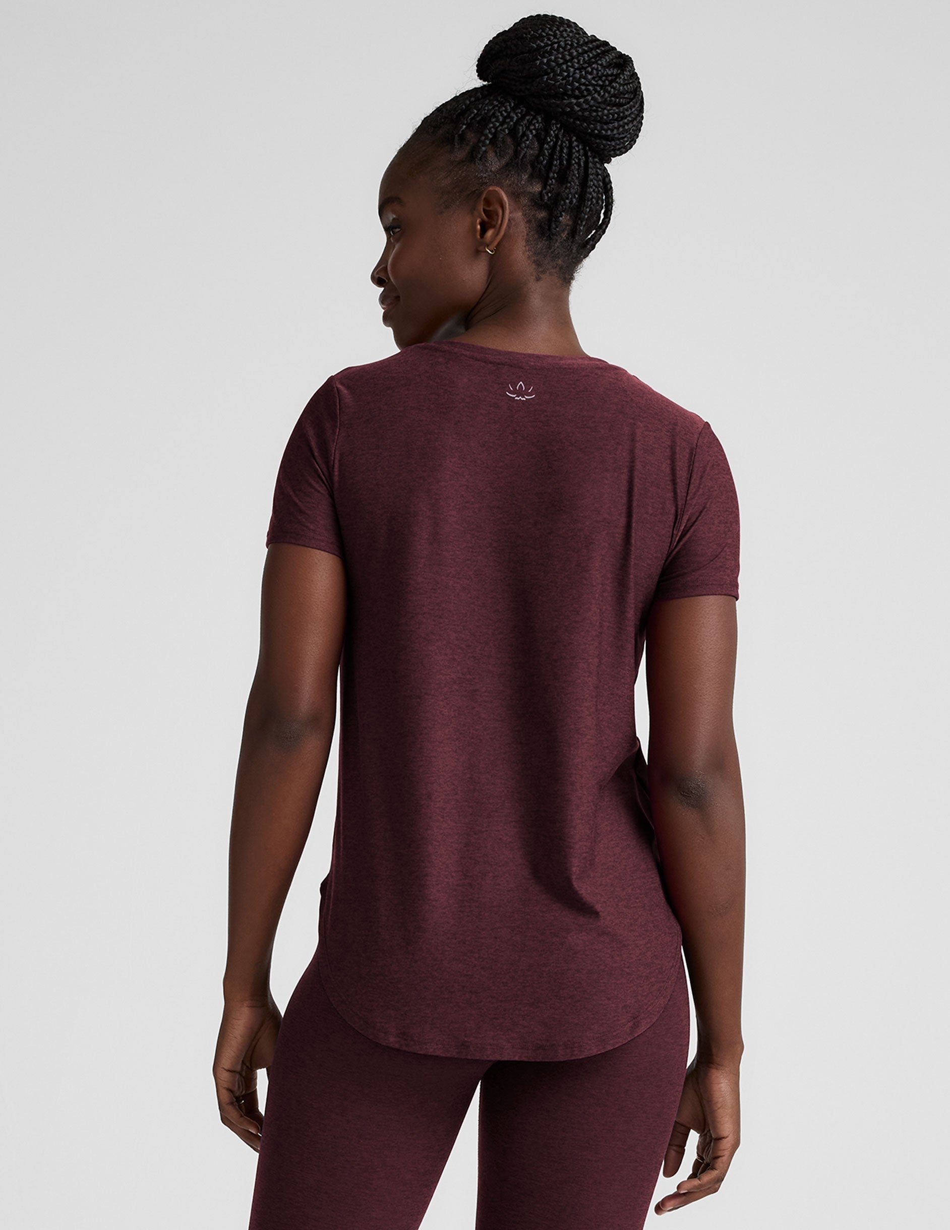 model is wearing a maroon t-shirt and leggings against a plain background.