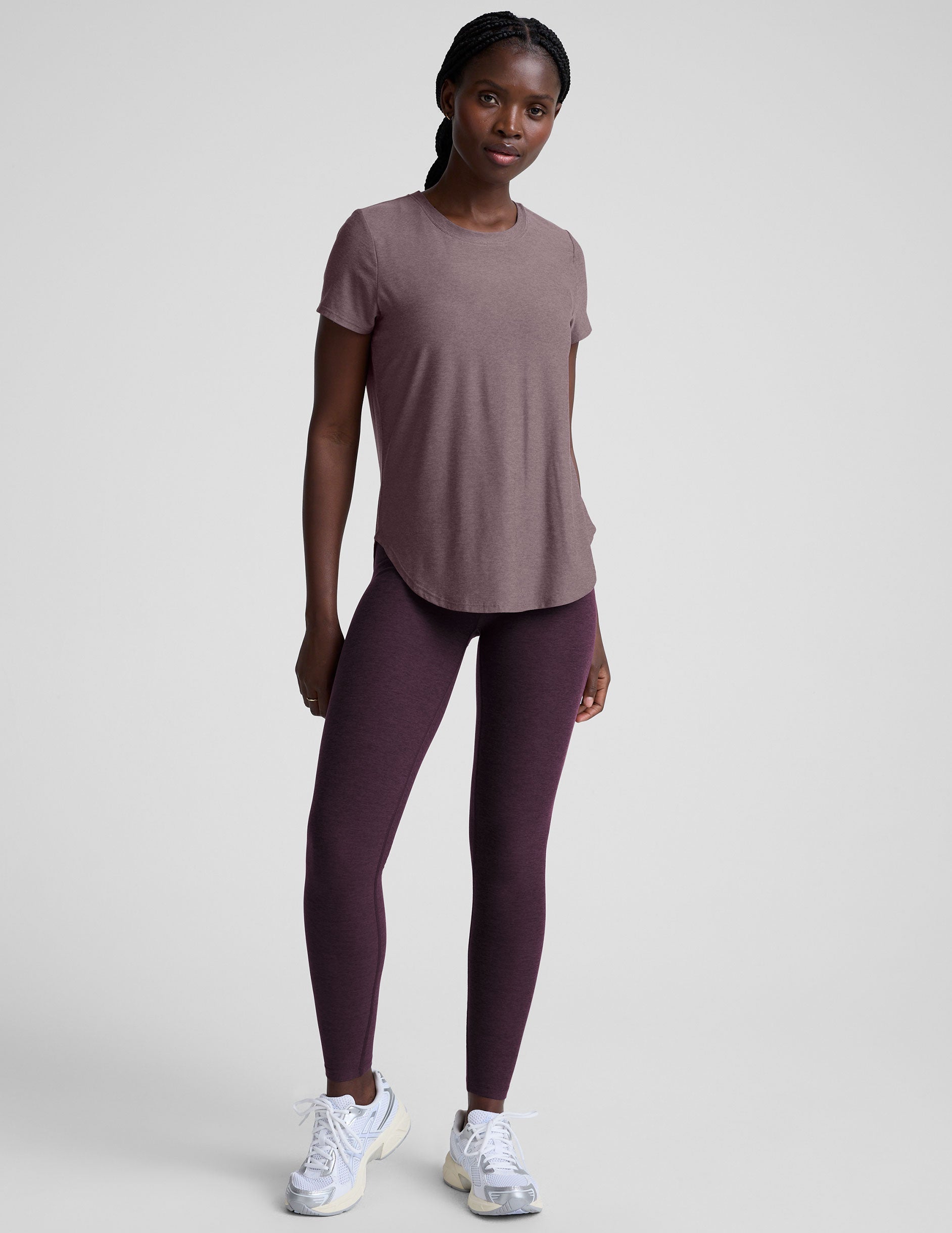 model wearing a mauve t-shirt and leggings on a plain background.
