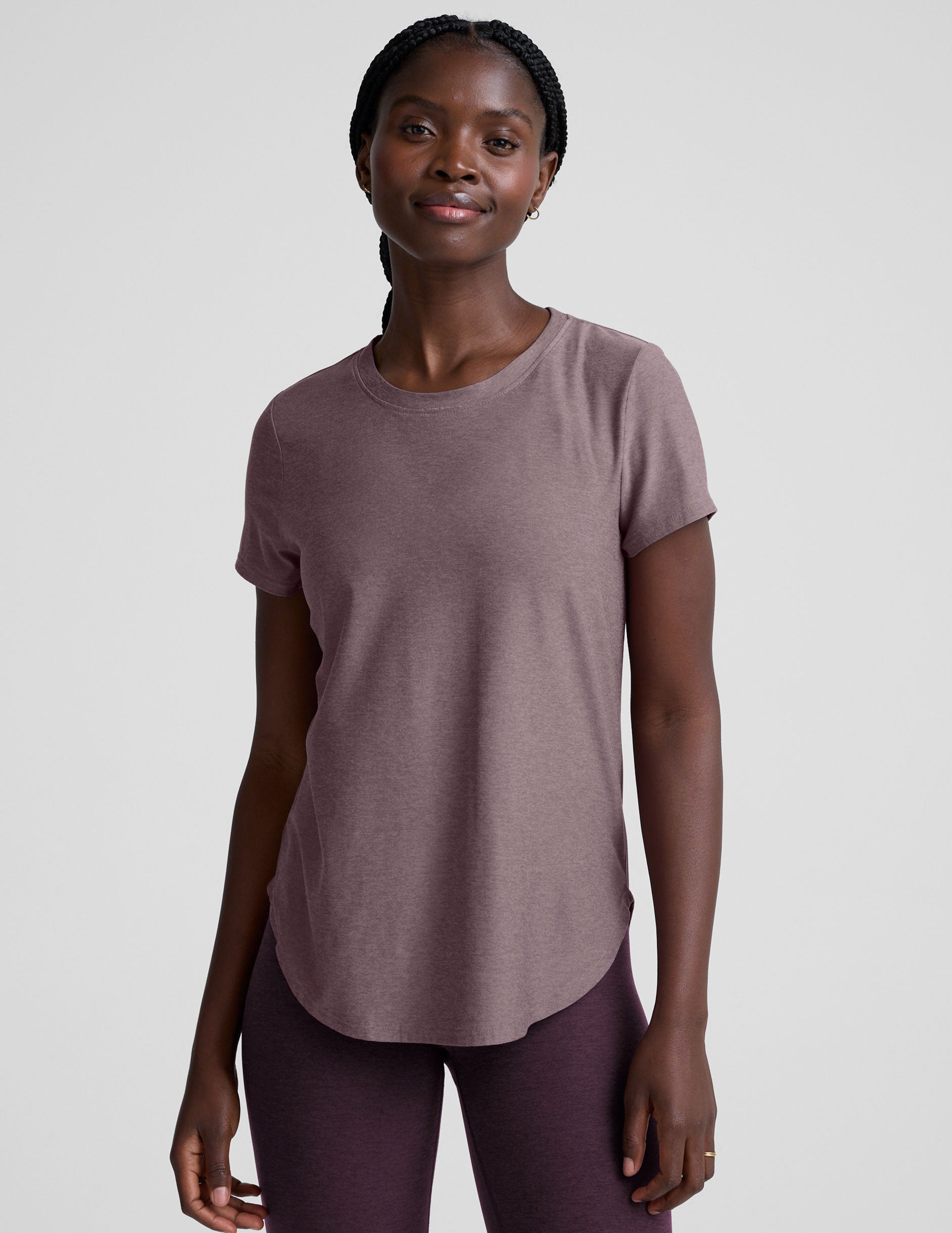 model wearing a mauve t-shirt and leggings on a plain background.