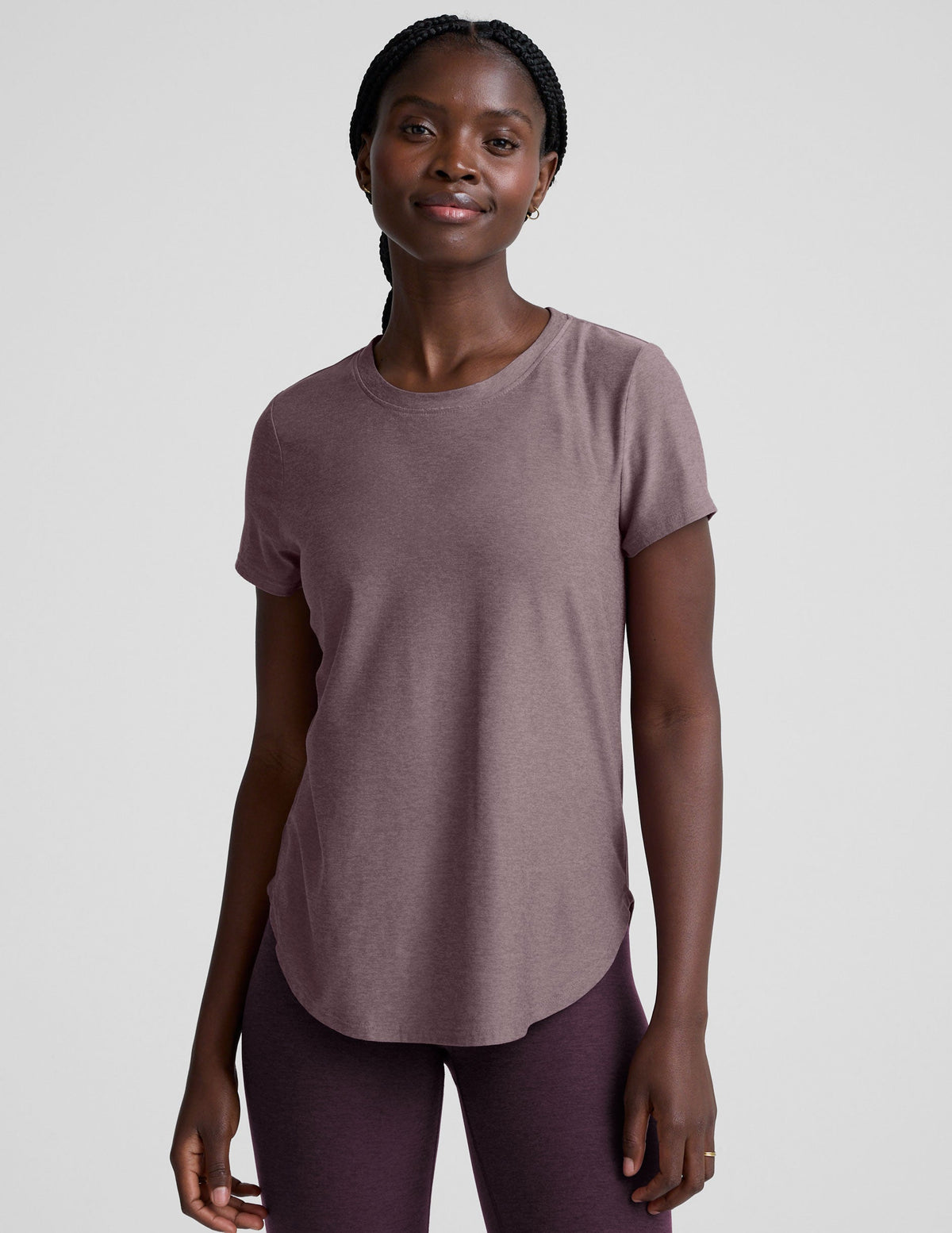 model wearing a mauve t-shirt and leggings on a plain background.