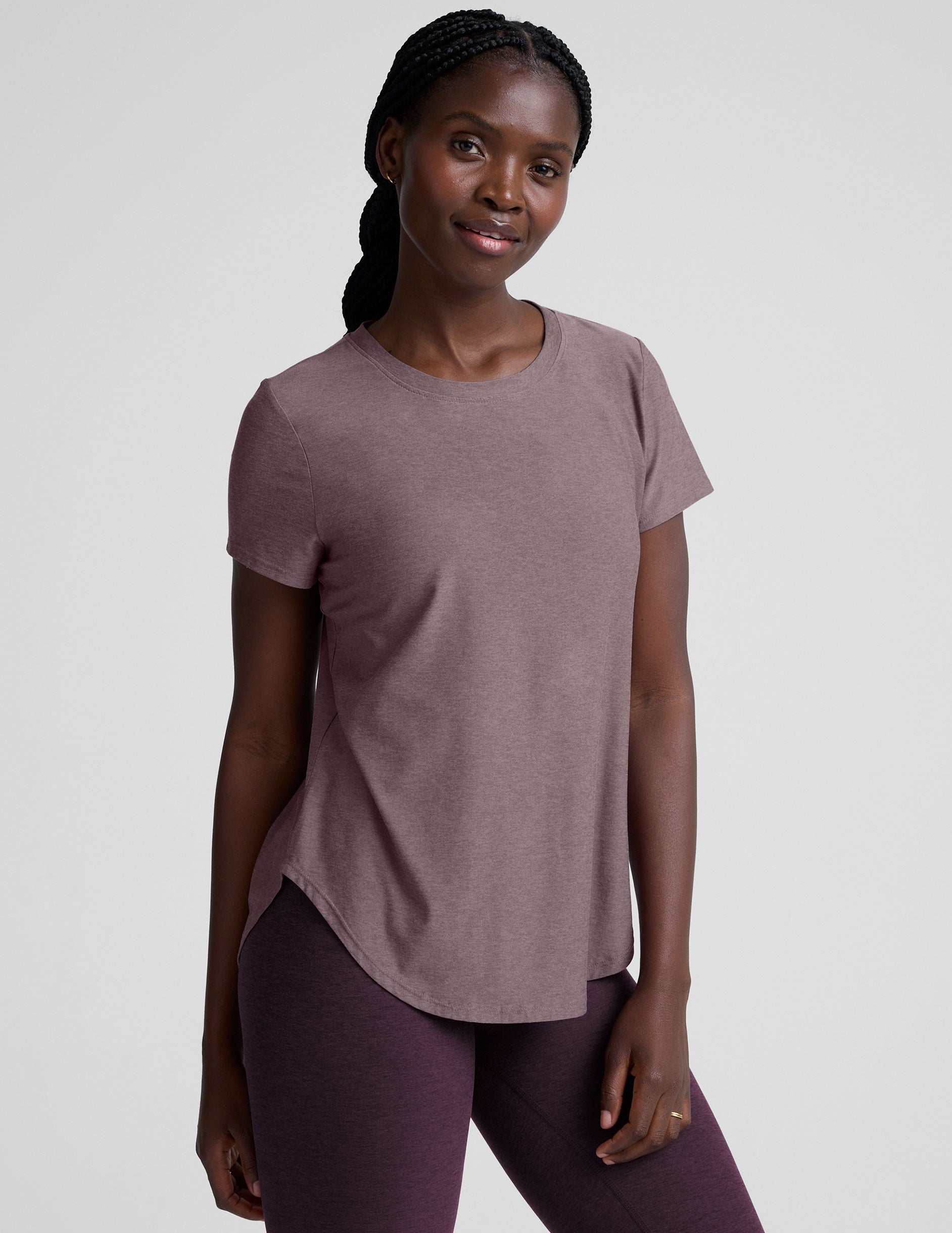 model wearing a mauve t-shirt and leggings on a plain background.