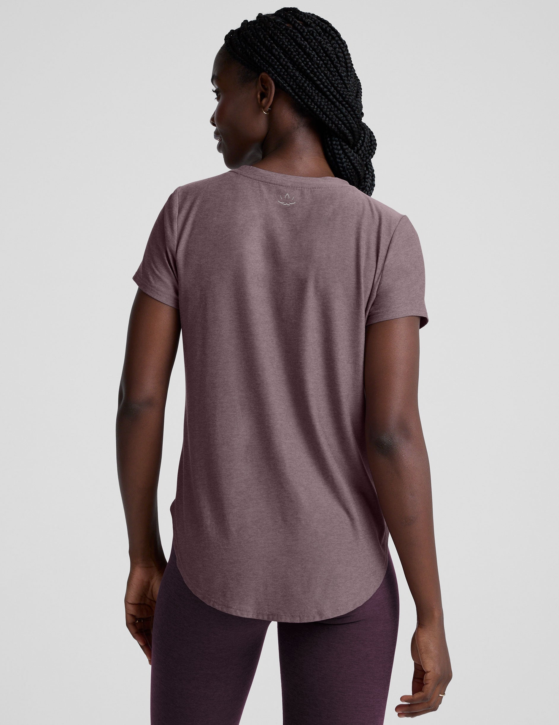 model wearing a mauve t-shirt and leggings on a plain background.