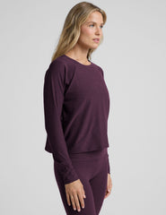 model wearing a purple scoop neck long-sleeve top and leggings on a light gray background.