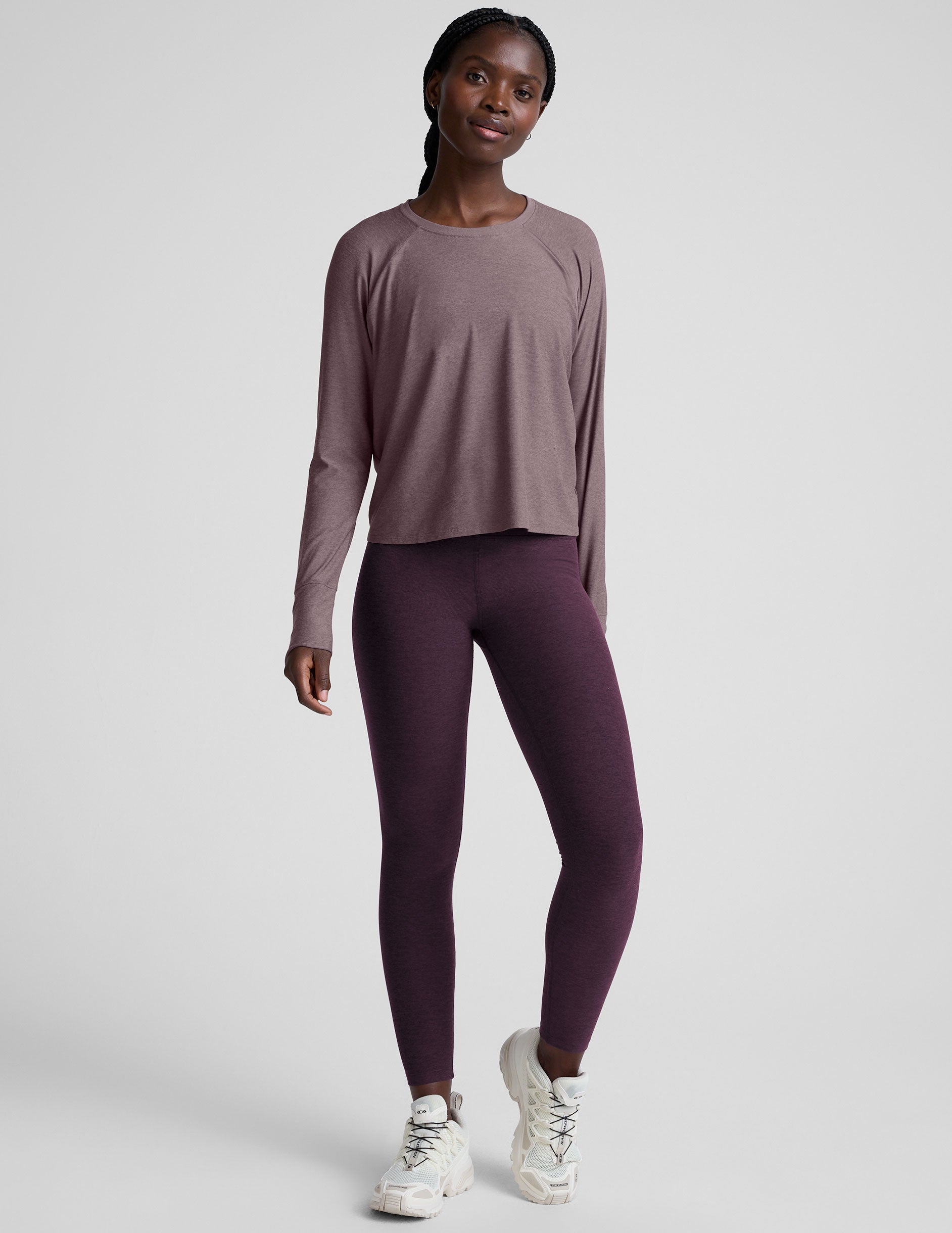model wearing a light purple scoop neck long-sleeve top and purple leggings on a light gray background.