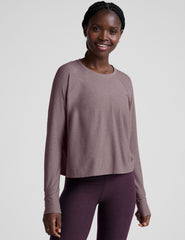 model wearing a light purple scoop neck long-sleeve top and purple leggings on a light gray background.