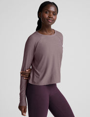 model wearing a light purple scoop neck long-sleeve top and purple leggings on a light gray background.