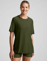 model wearing a green oversized men's t-shirt and biker shorts against a plain background.